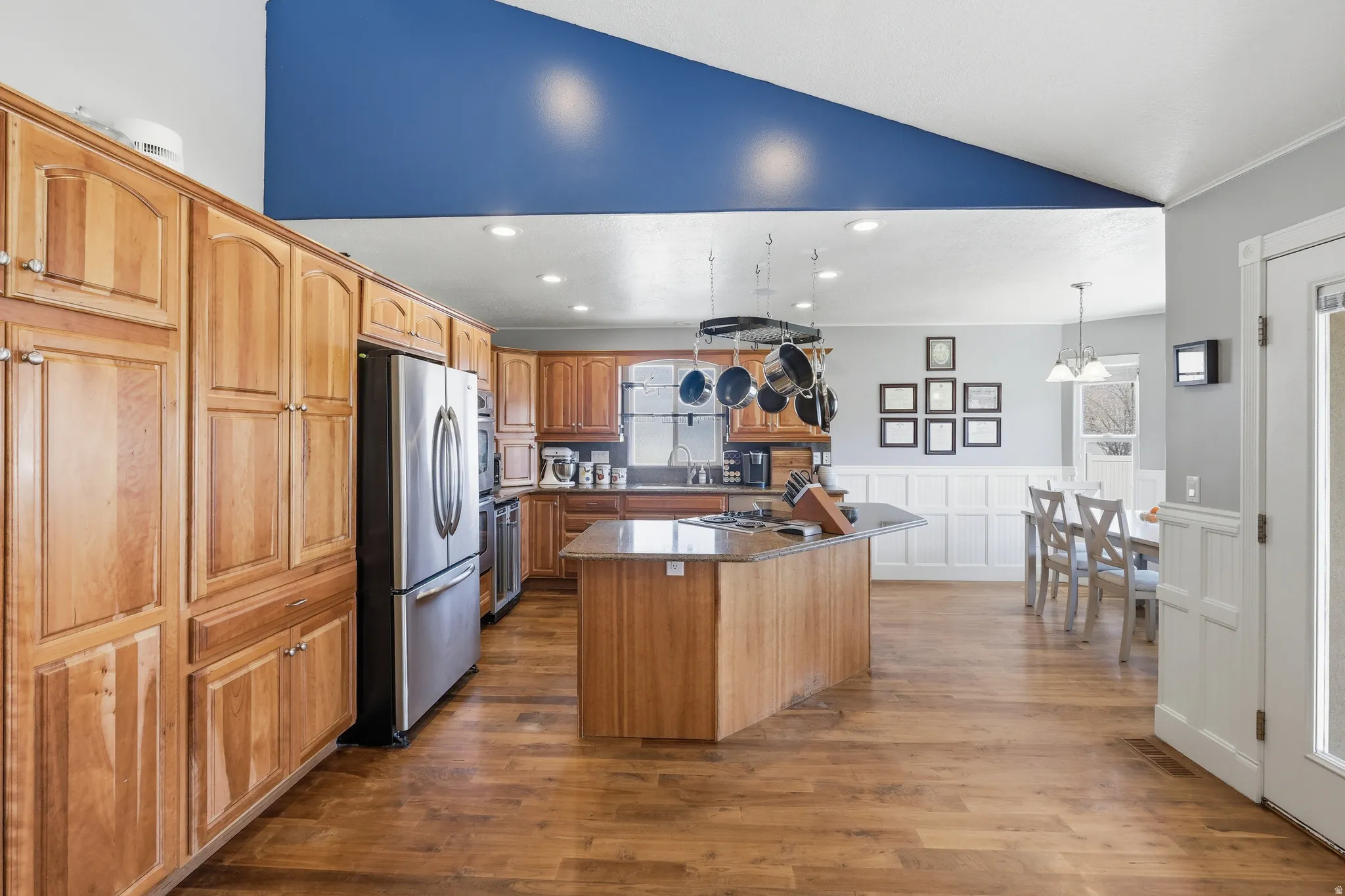 Open-concept kitchen with wood-finish flooring, extensive cabinetry, and stainless steel appliances