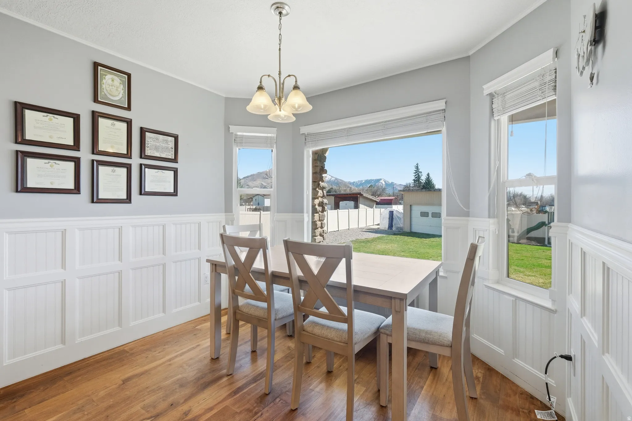 Dining area featuring wood-finish flooring, white wainscoting, and large windows