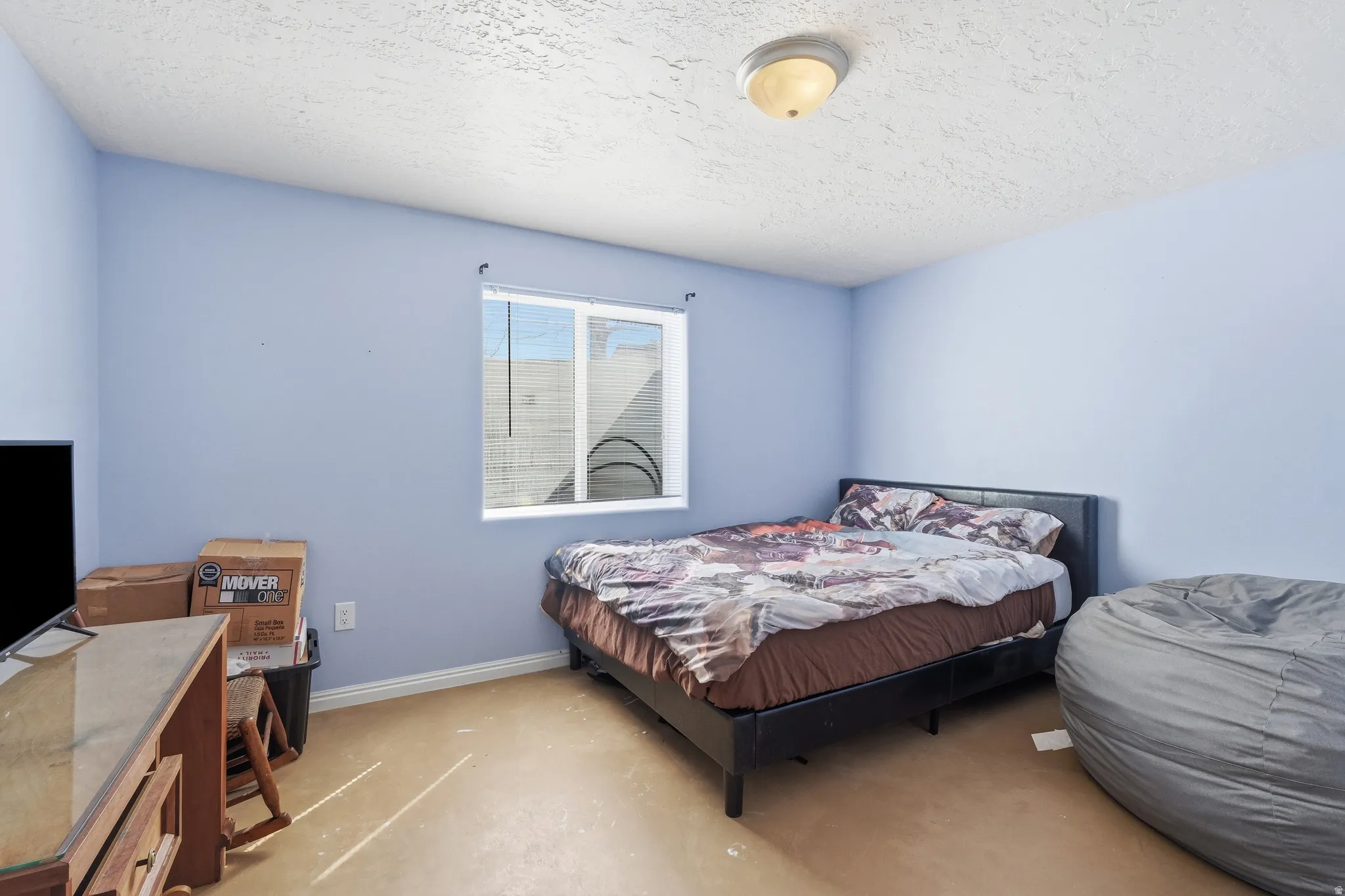 Bedroom featuring a window, textured ceiling, and light-colored walls