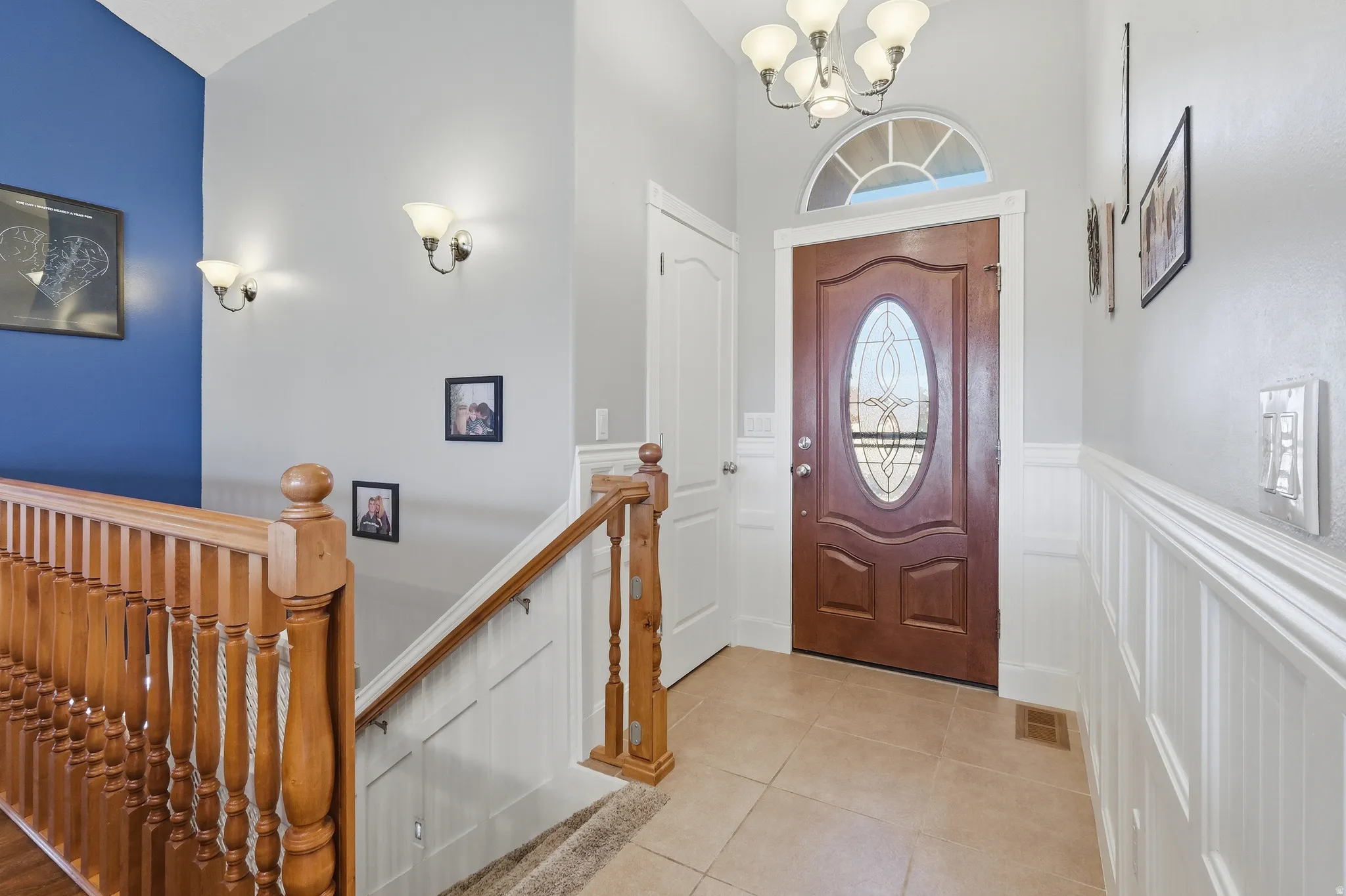 Foyer featuring a wood-finish entry door with an oval leaded glass insert, an arched transom window, and tiled flooring