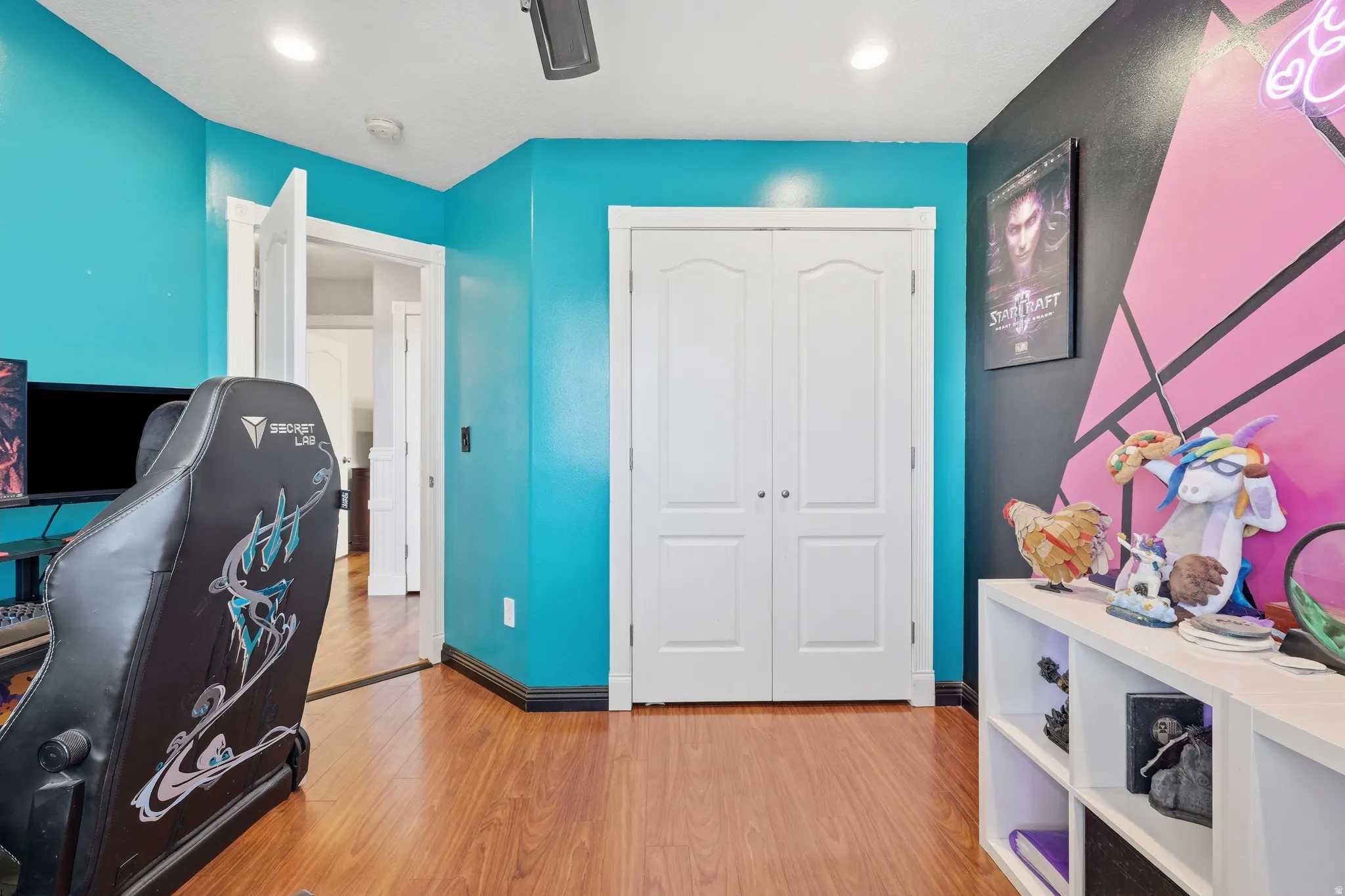 Room featuring wood-finish flooring, two-panel bifold closet doors, a recessed ceiling light, a ceiling fan, and painted walls