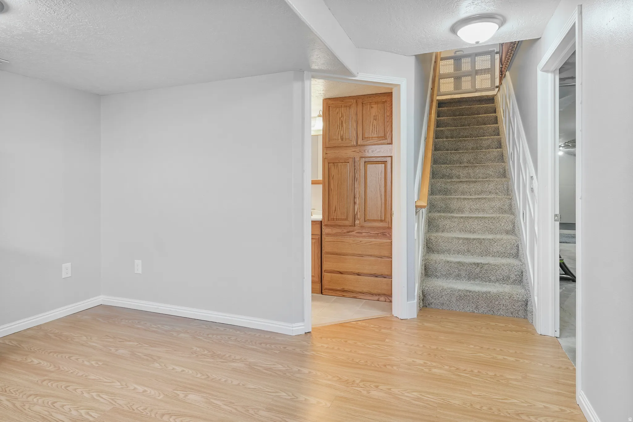 Staircase with carpeted treads and white risers, featuring a wood handrail