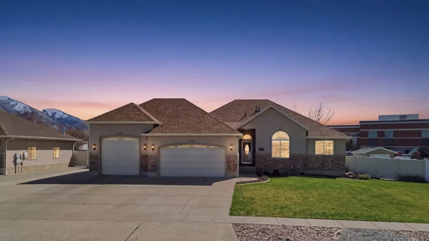 Ranch-style residence featuring a stucco and stone veneer exterior, an arched entry, and two garage bays with carriage-style doors