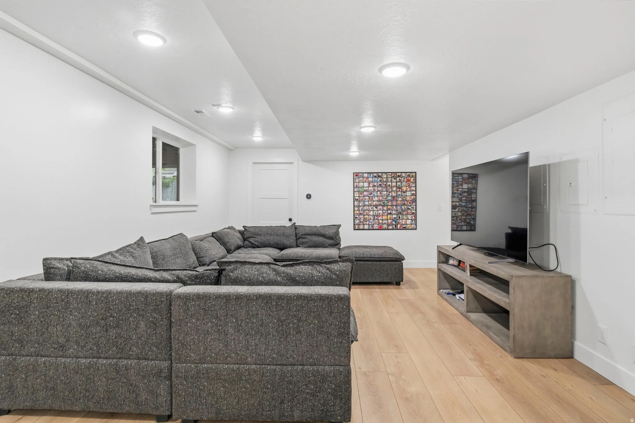 Lower-level recreation space featuring light wood-finish flooring, white walls, and recessed lighting