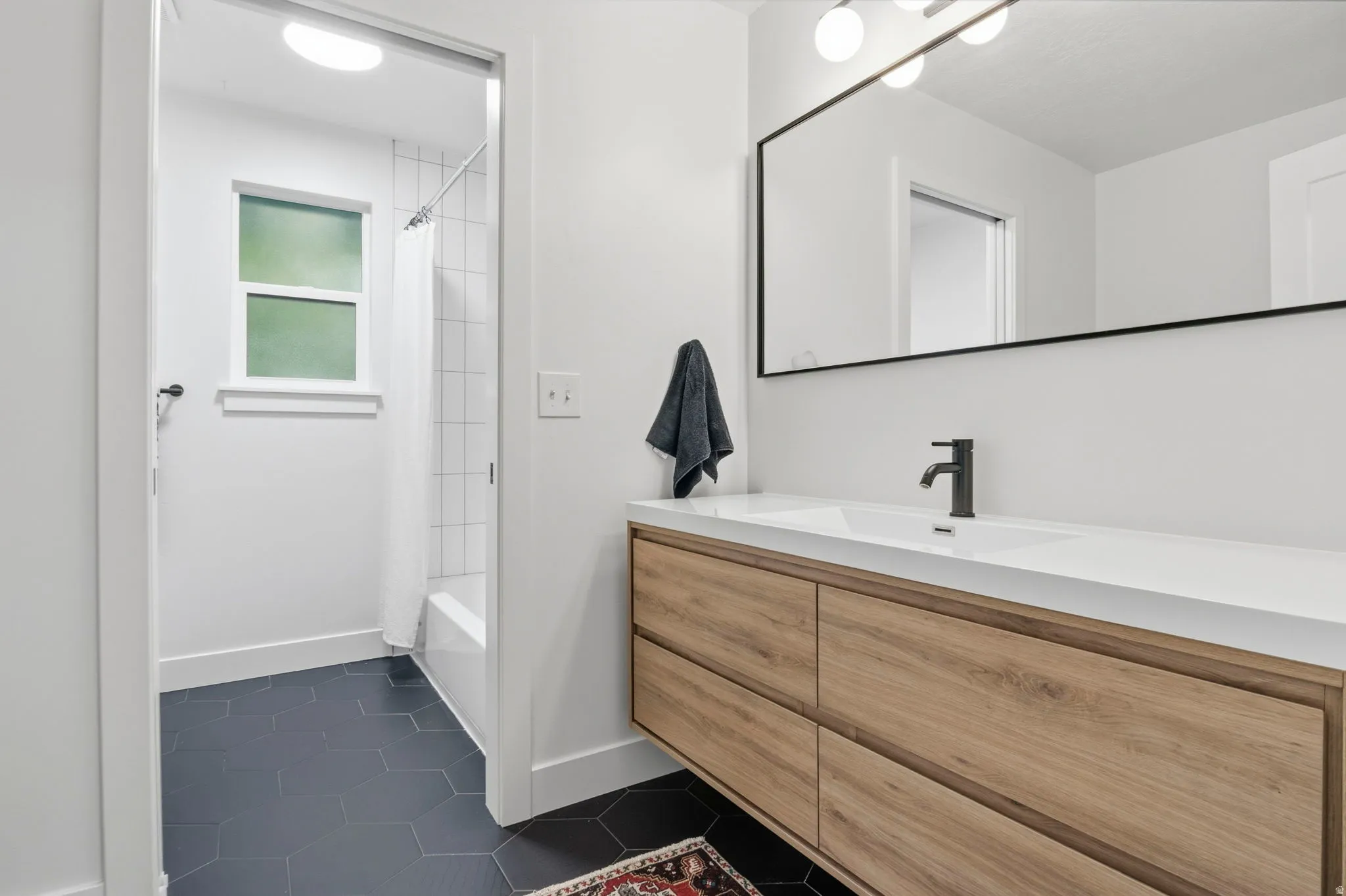 Modern bathroom vanity featuring a light wood-finish with integrated rectangular sink and matte black faucet