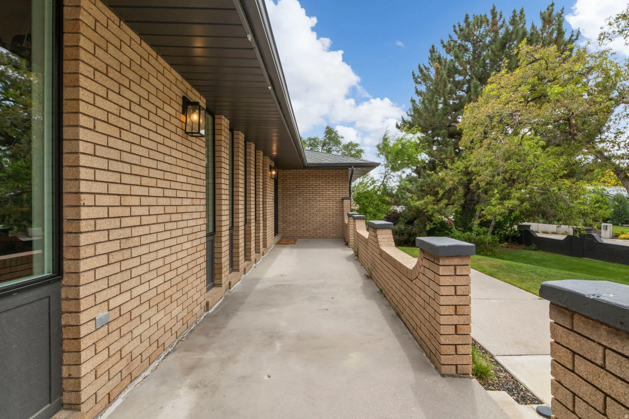 Brick exterior featuring a covered walkway, decorative wall sconces, and a concrete pathway