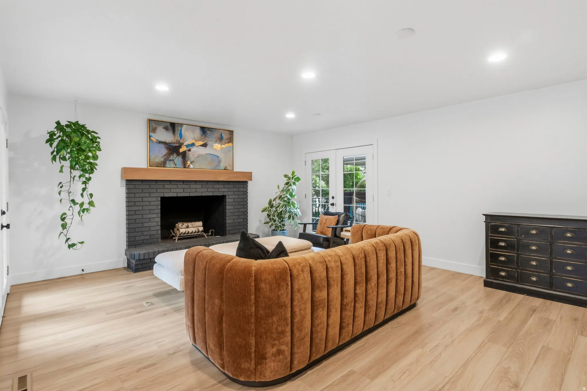 Living area featuring a dark brick fireplace with a wood mantel, light wood-finish flooring, recessed lighting, and white walls
