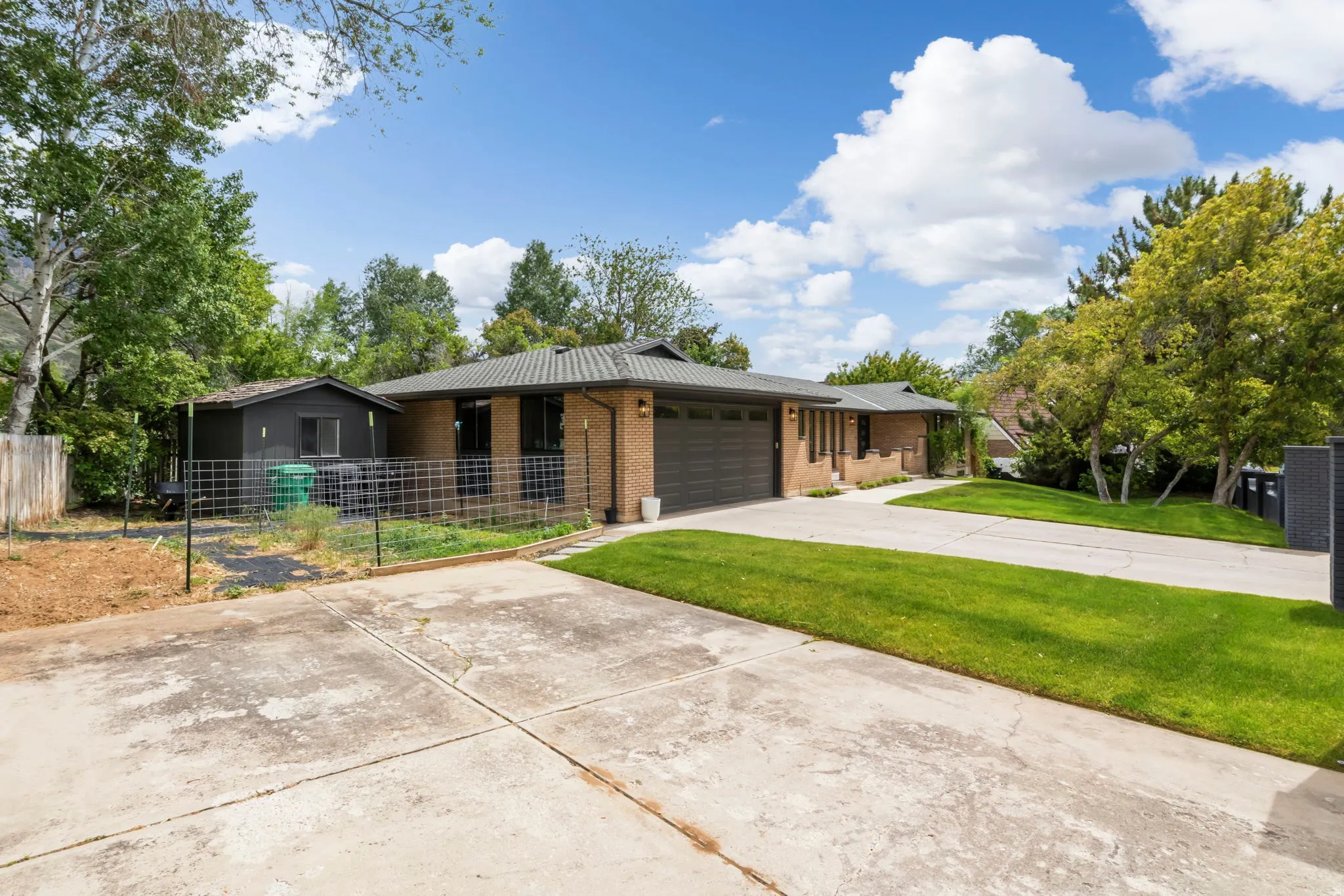 Brick exterior with an attached garage, featuring a concrete driveway and a grassy front lawn