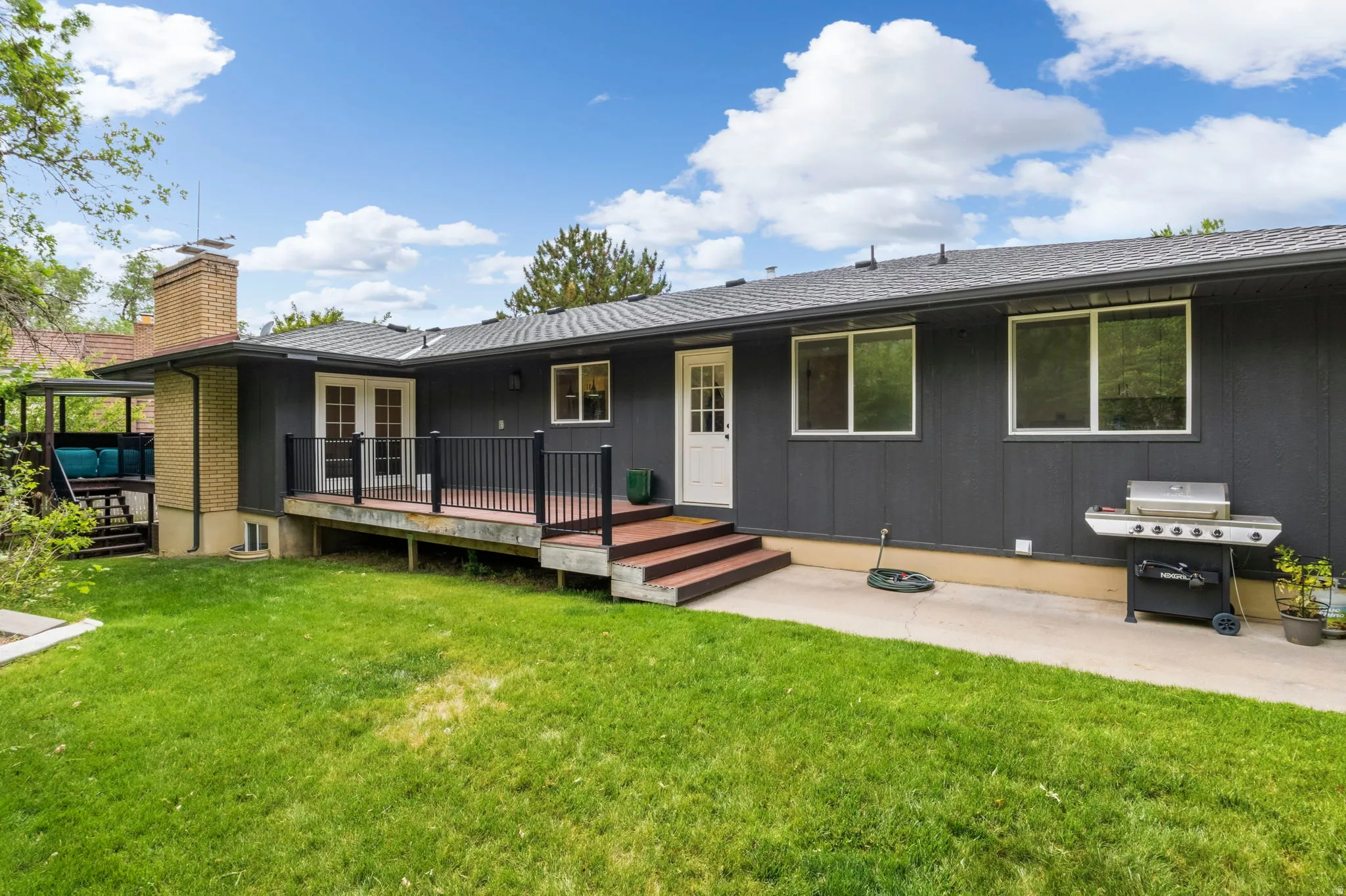 Expansive green lawn bordering a multi-level deck with dark railings and a secondary covered patio