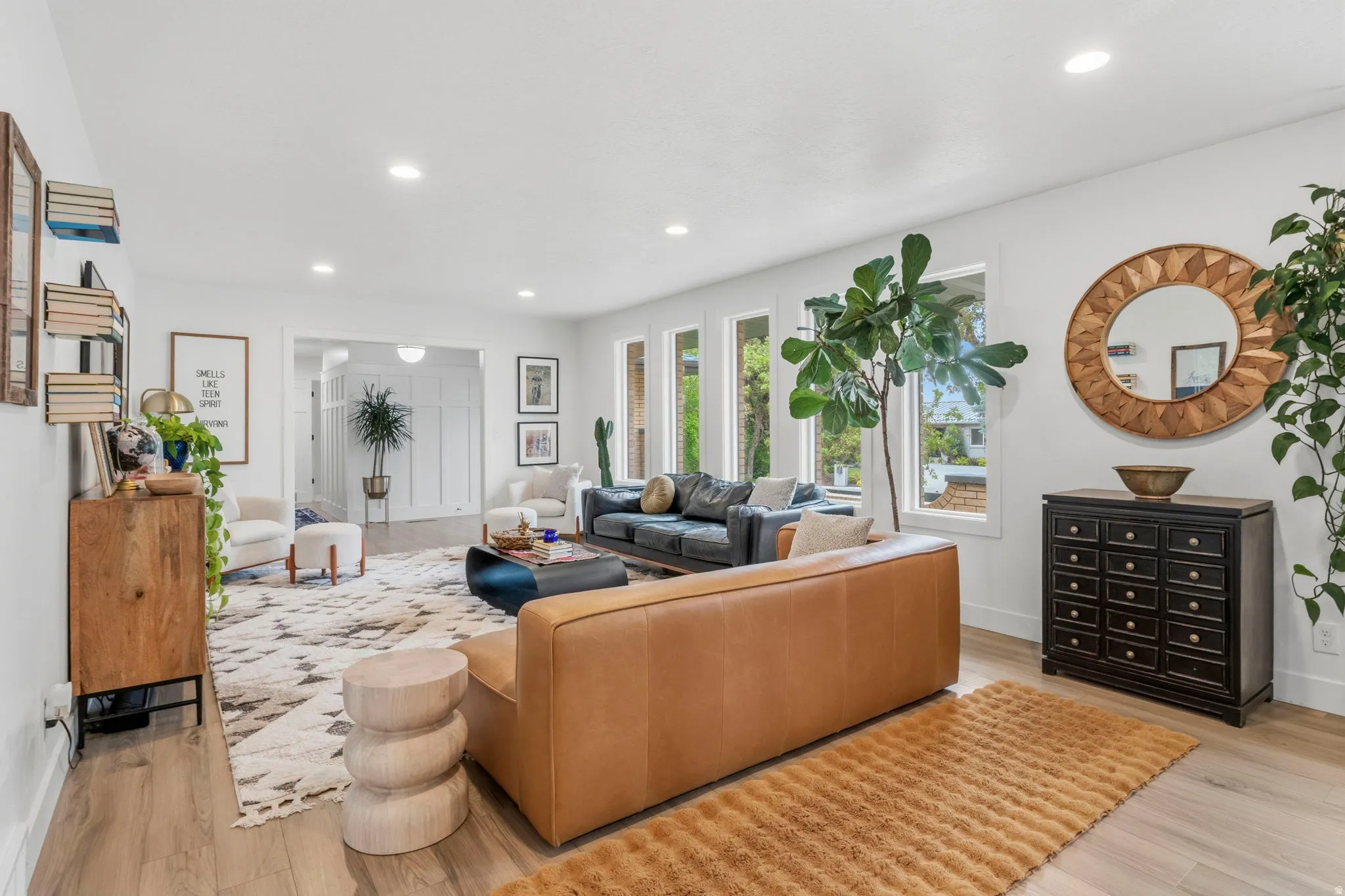 Spacious living area featuring light wood-finish flooring, recessed lighting, and multiple large windows