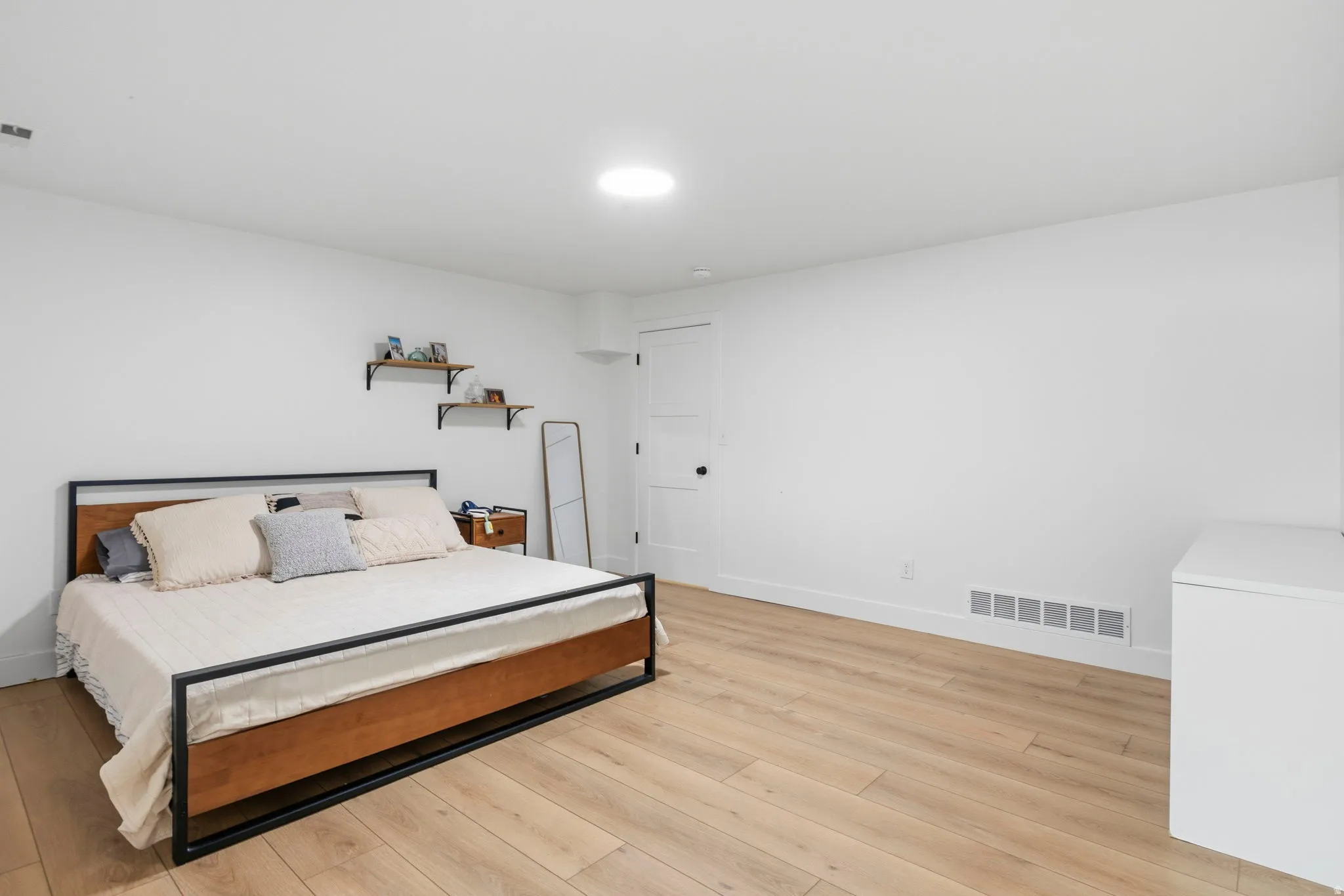Spacious room featuring light wood-finish flooring, white walls, and a recessed ceiling light