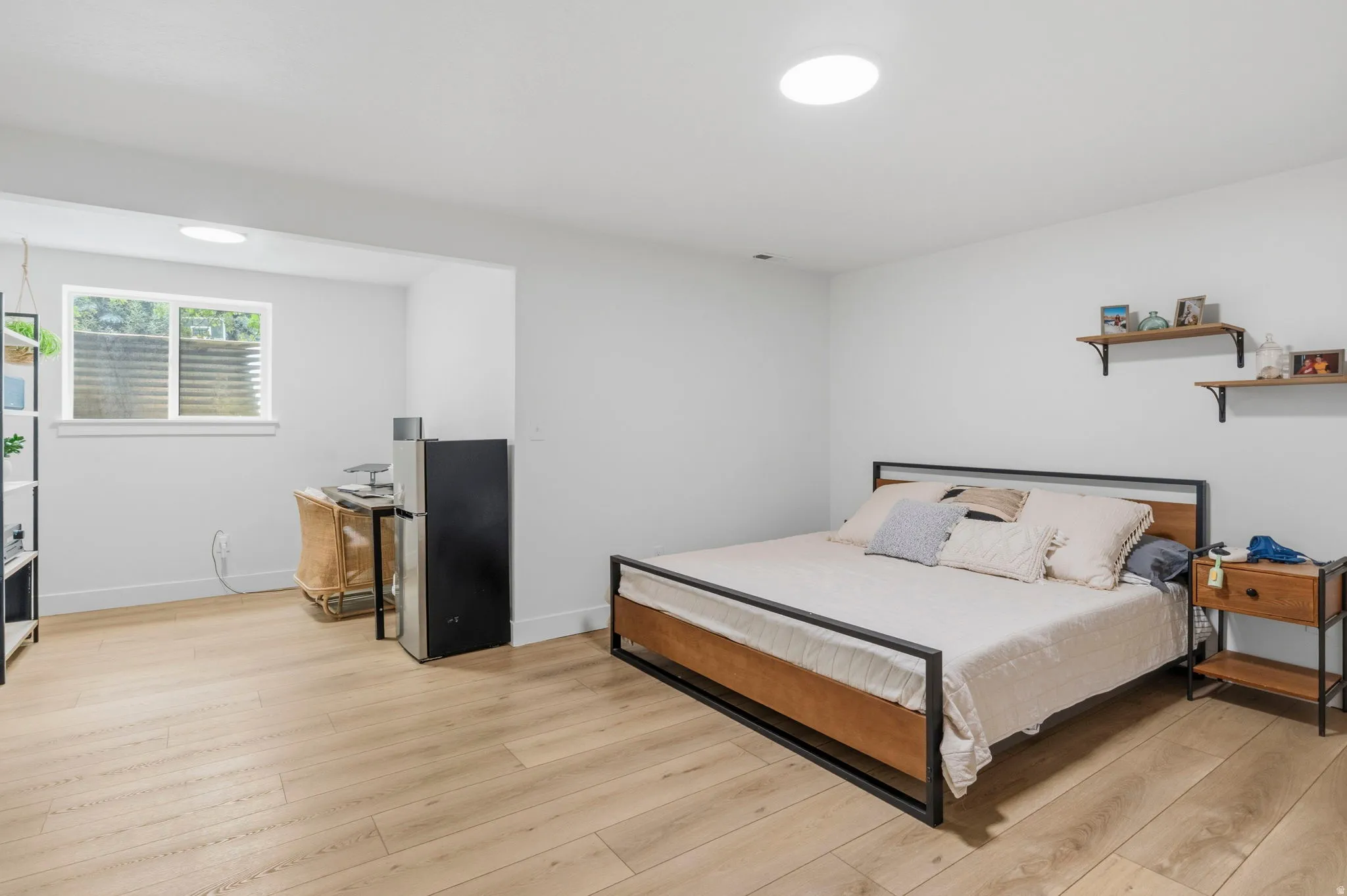 Spacious room with light wood-finish flooring, recessed lighting, and a window providing natural illumination