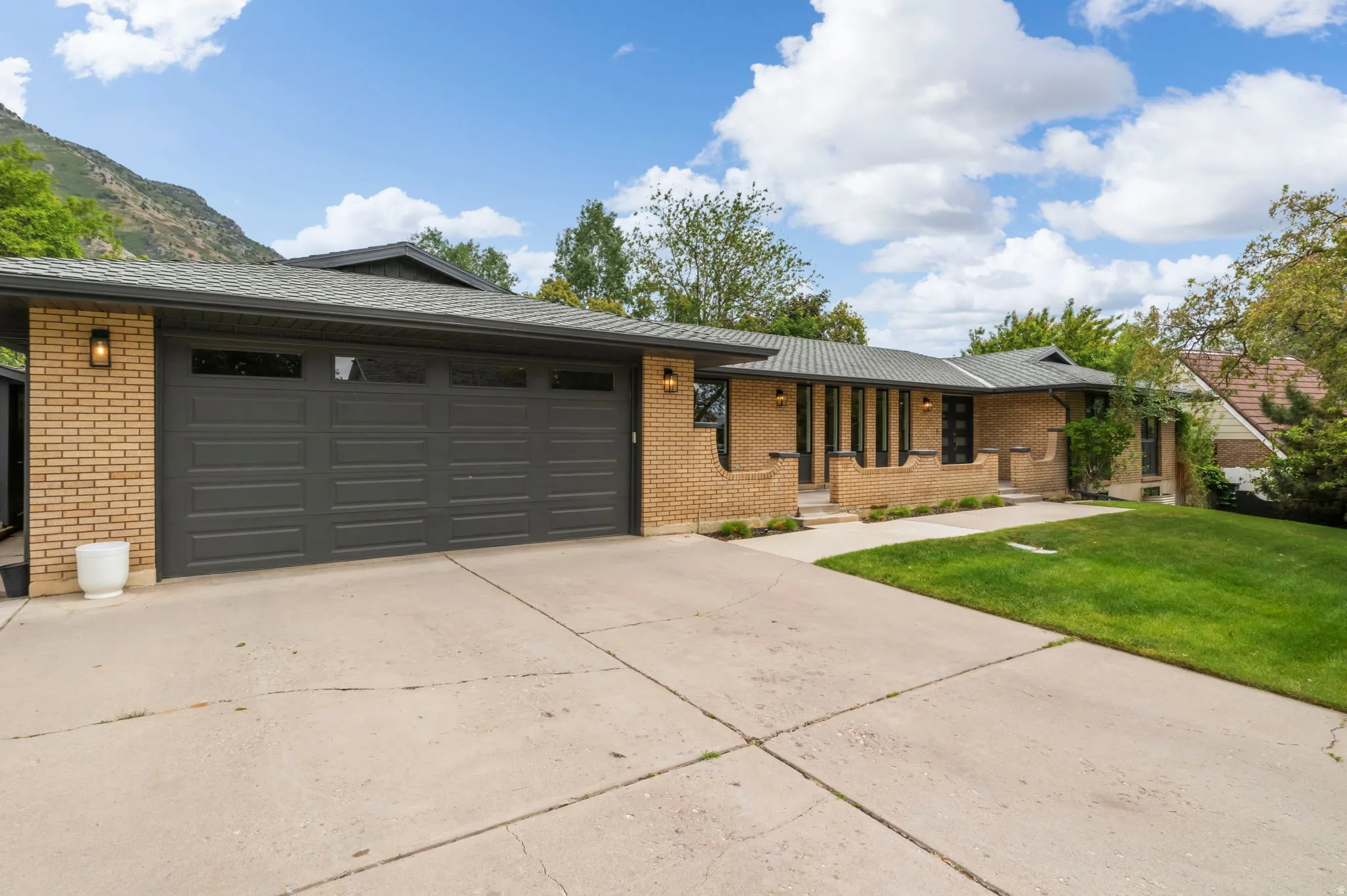Brick exterior featuring a multi-car garage, concrete driveway, and front lawn