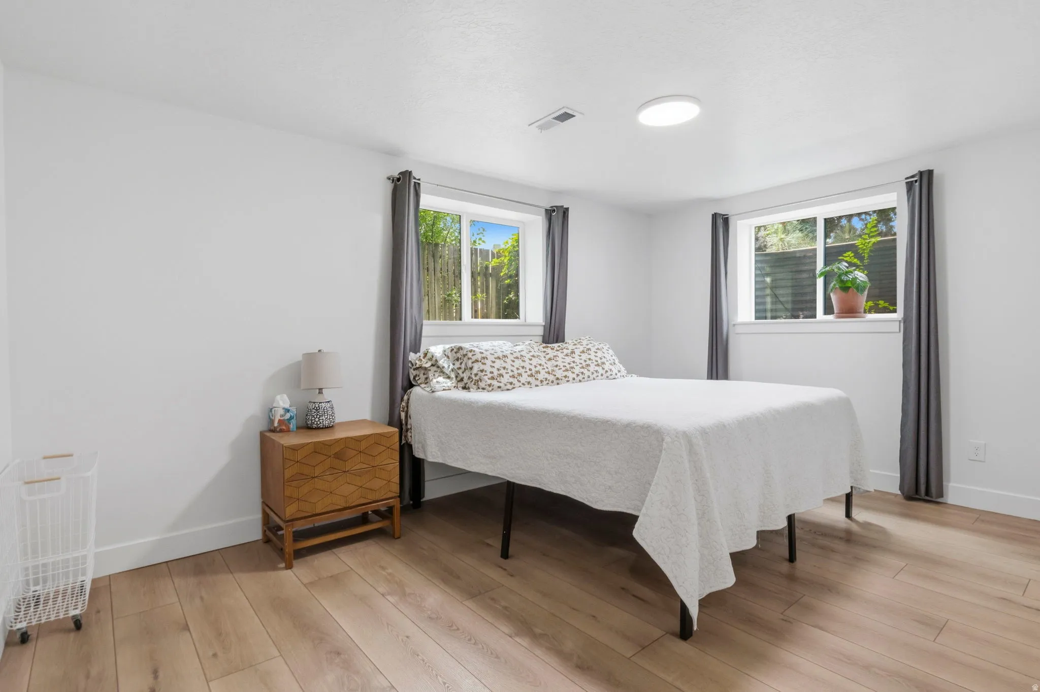 Bedroom with light wood-finish flooring, white walls, and a contemporary ceiling light fixture