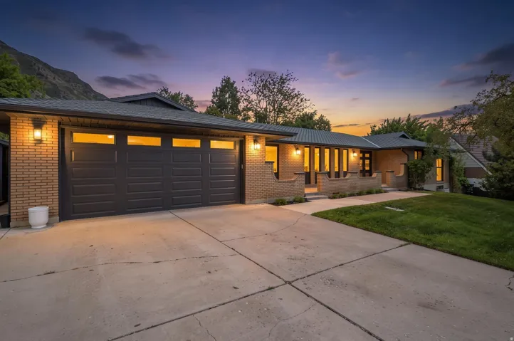 Brick exterior featuring a multi-panel garage door with transom windows, a concrete driveway, and front landscaping