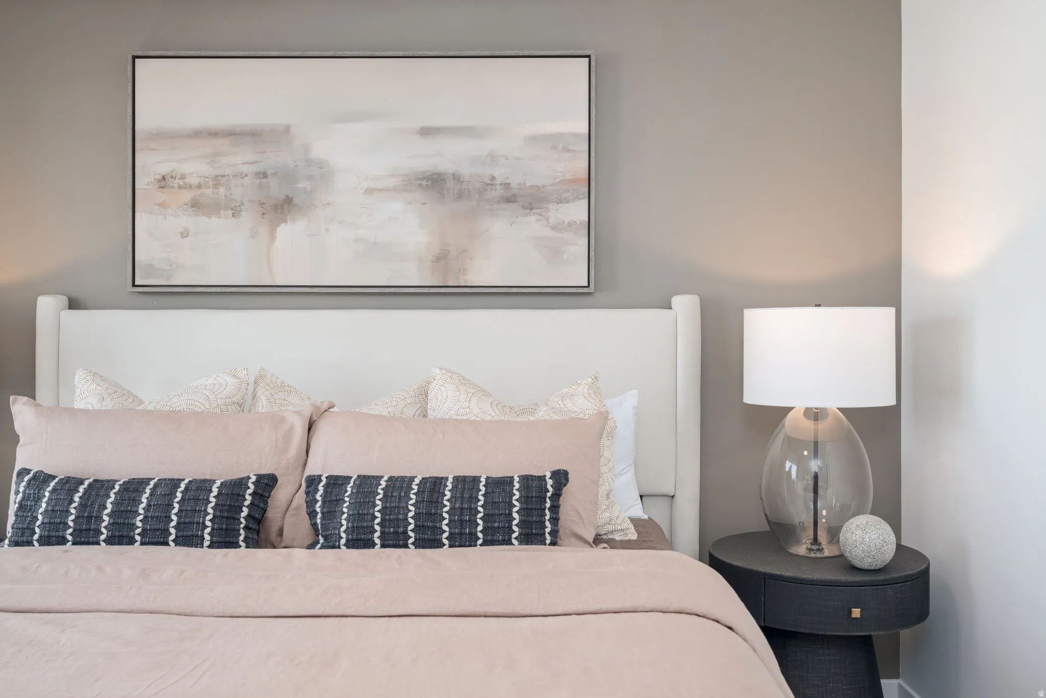 Upholstered headboard with clean lines, accent wall with neutral paint, and built-in bedside table with integrated drawer