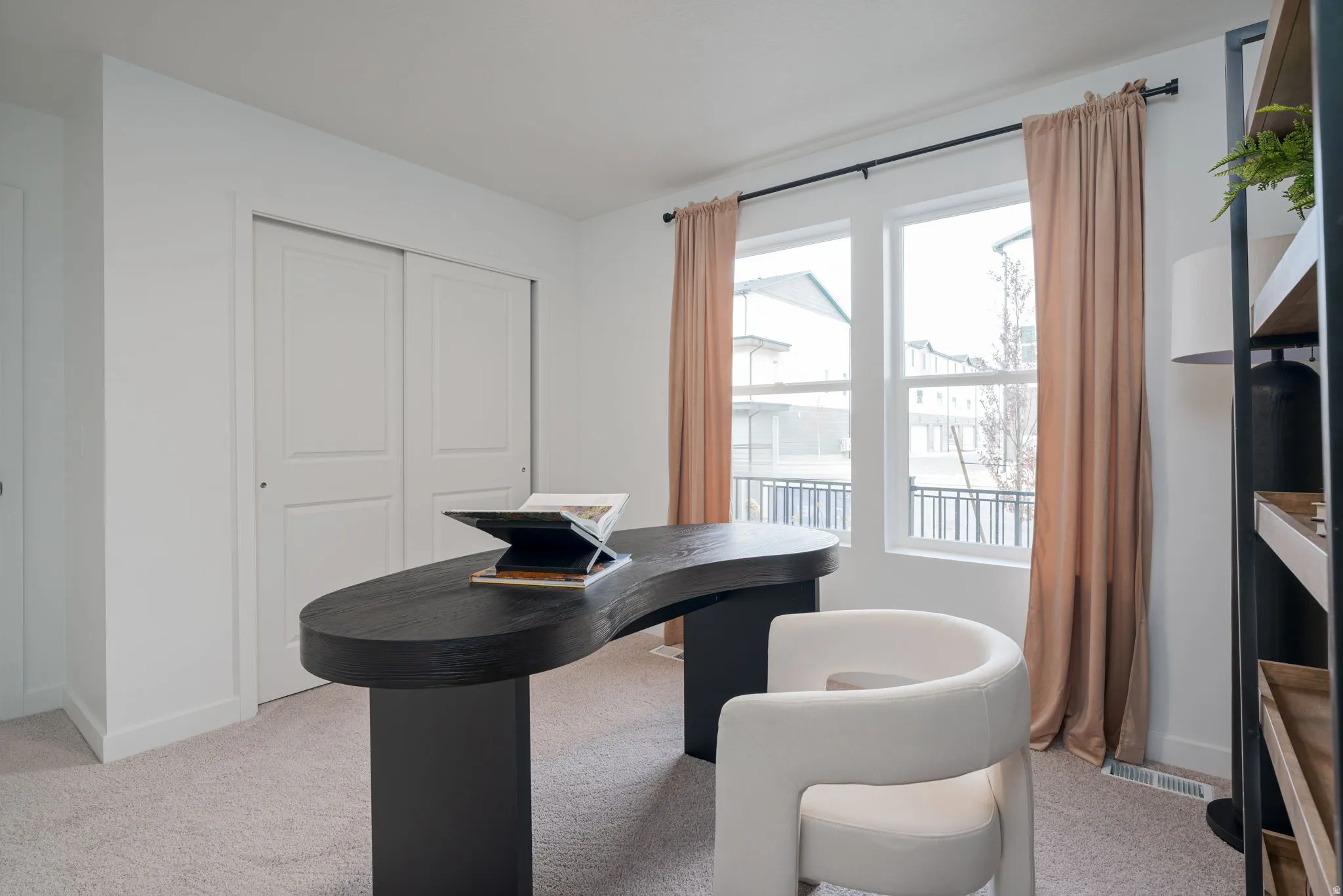 Bright room featuring two large windows with full-length drapery, white walls, and light-toned carpeting