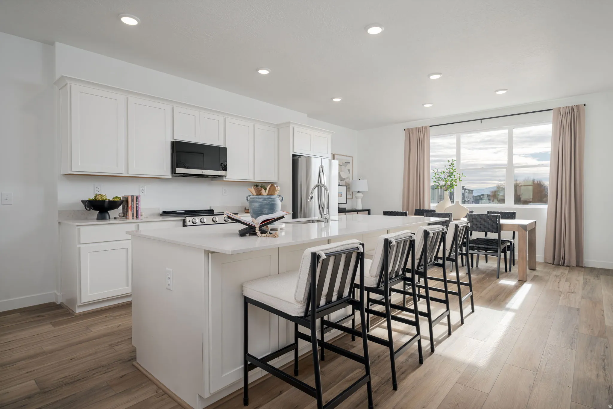 Contemporary kitchen featuring white cabinetry, a large kitchen island with seating, stainless steel appliances, and wood-finish flooring