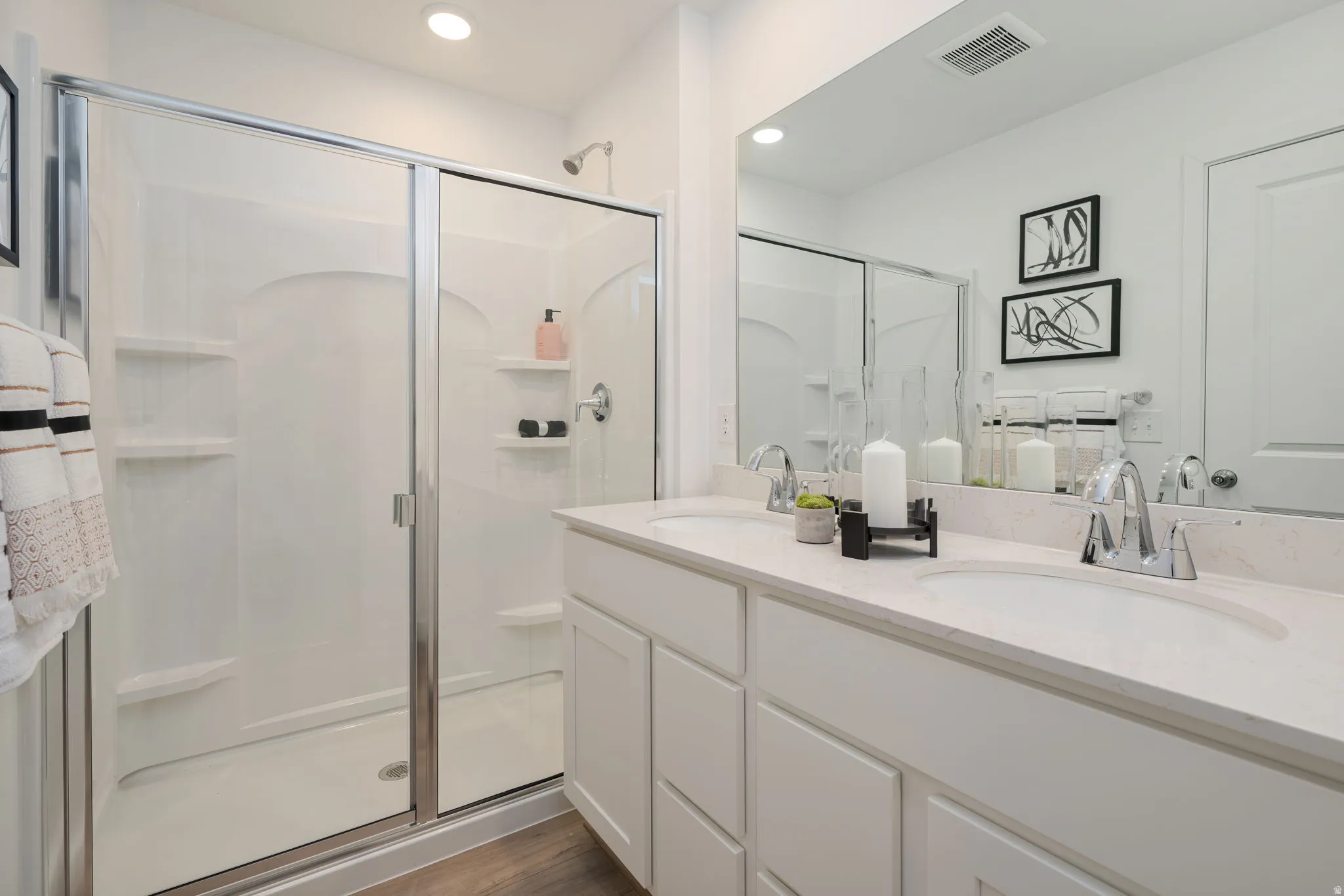 Bathroom featuring a dual vanity with white cabinetry, integrated sinks, and chrome faucets
