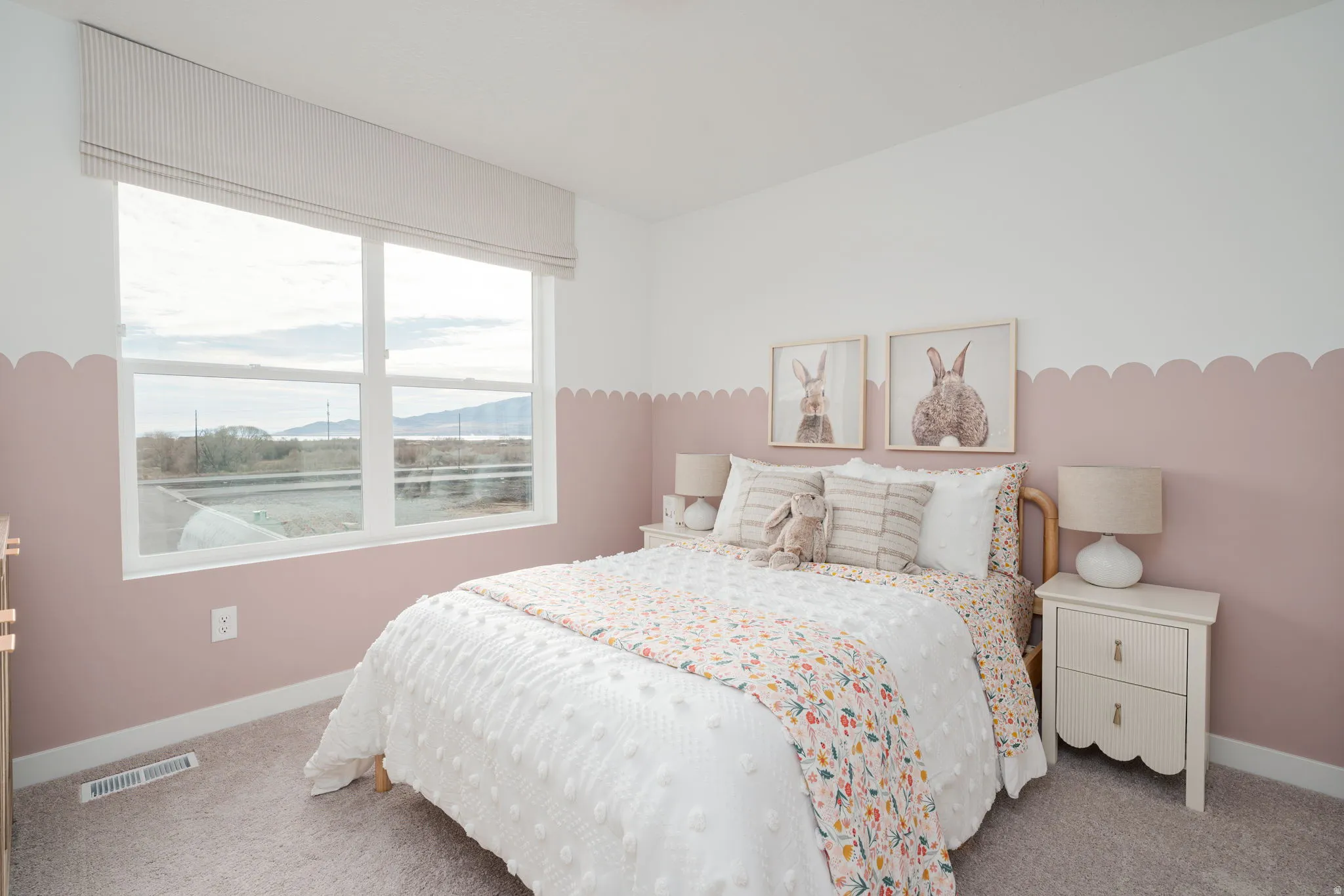 Bedroom featuring a large window, light gray carpeting, and a two-tone wall design with a scalloped accent