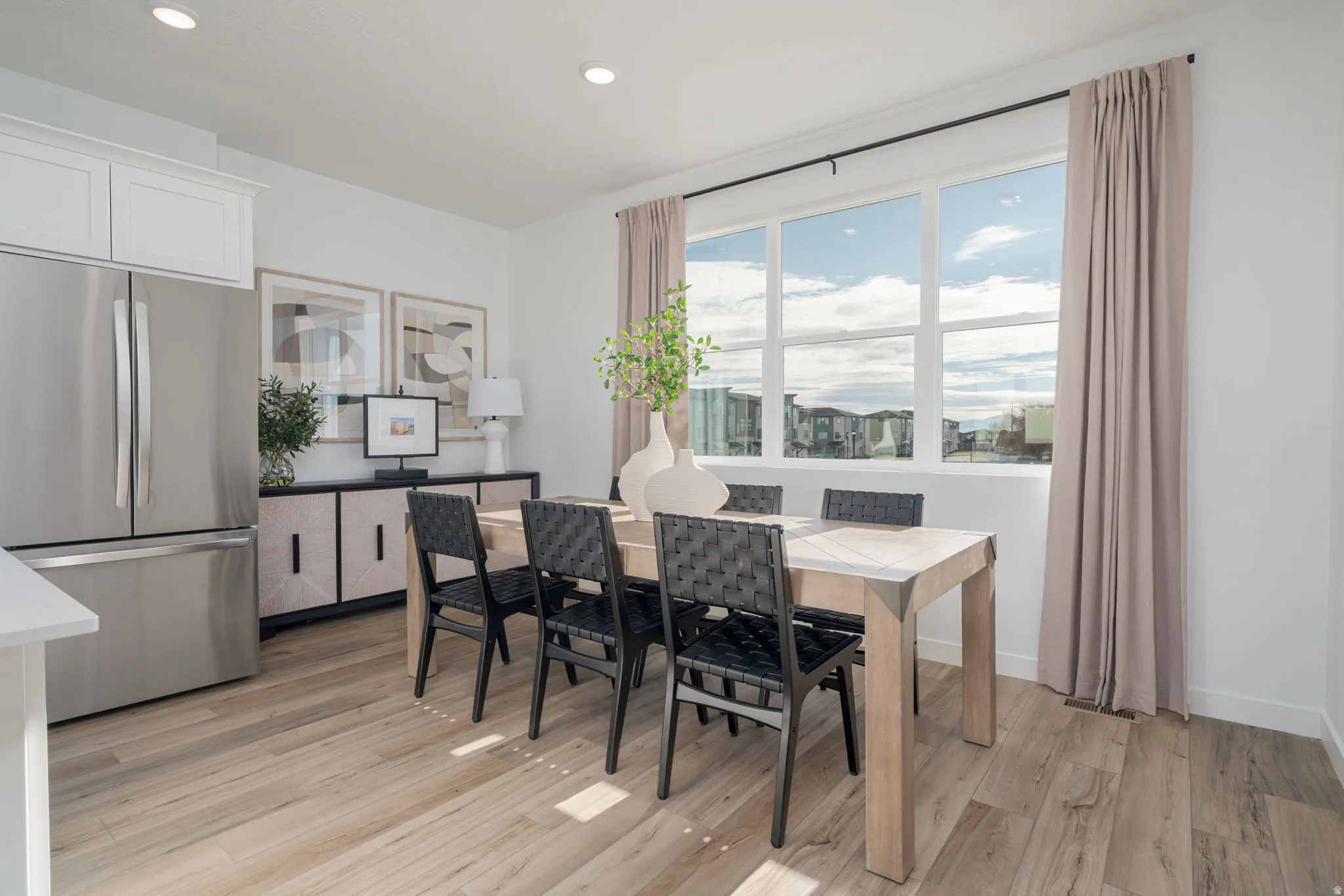 Bright dining area featuring a large picture window, wood-finish flooring, recessed lighting, and a built-in sideboard with integrated cabinetry