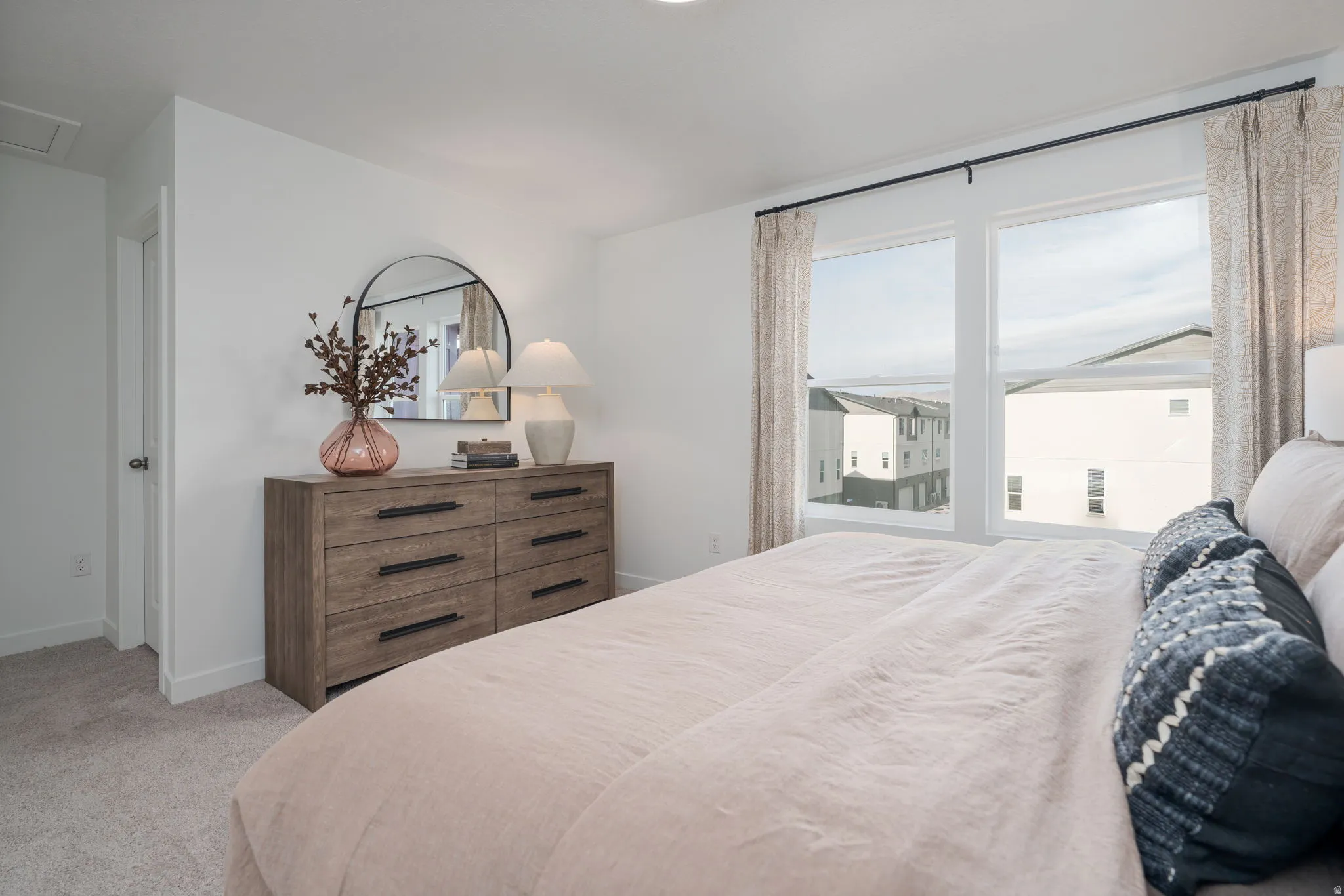 Bright bedroom featuring white walls, carpet flooring, and a large window with white trim