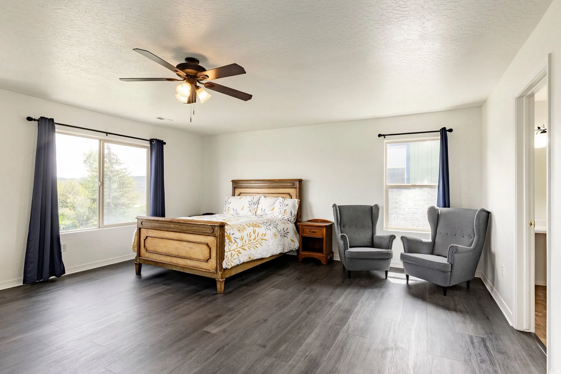 Spacious room featuring wood-finish flooring, white walls, and a ceiling fan with integrated lighting