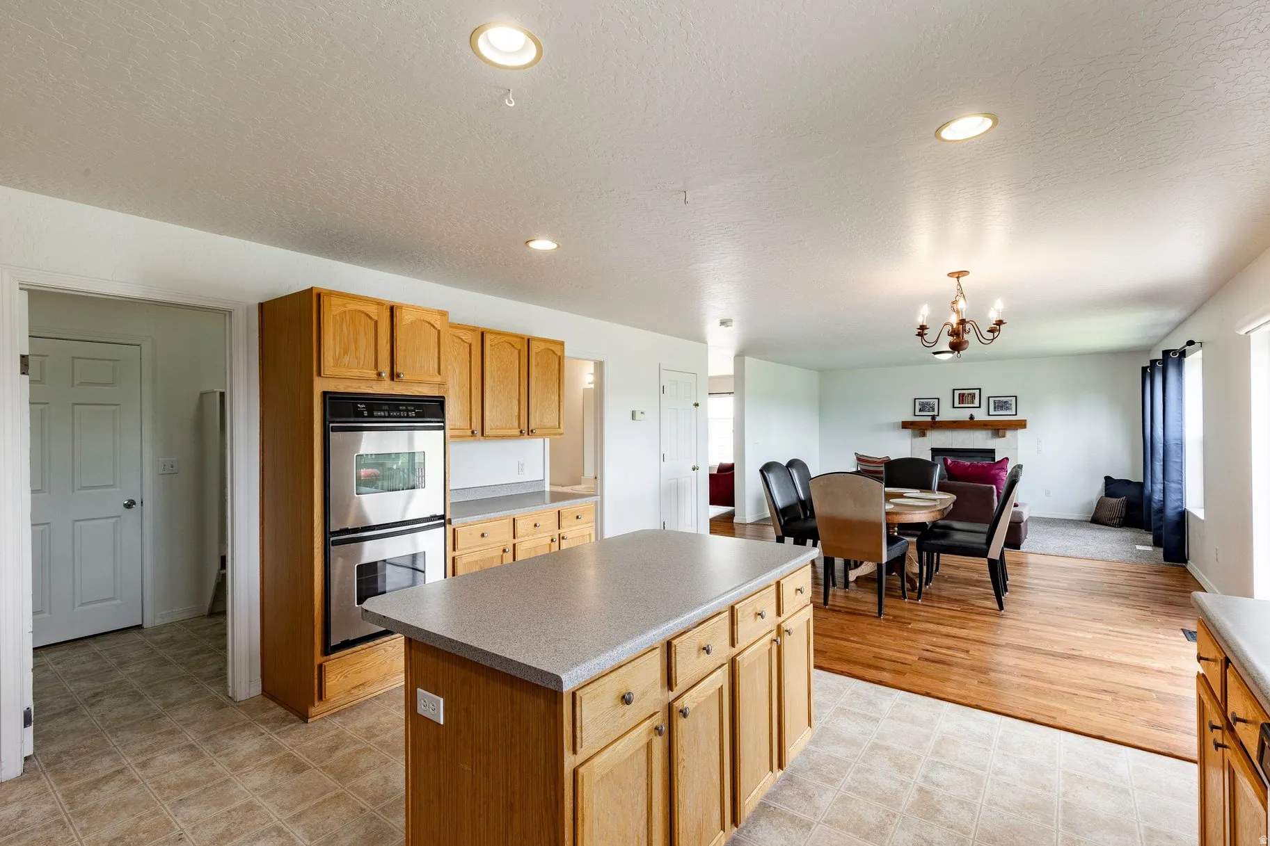 Kitchen featuring a central island with built-in cabinetry, stainless steel double wall ovens, wood cabinetry, and recessed lighting