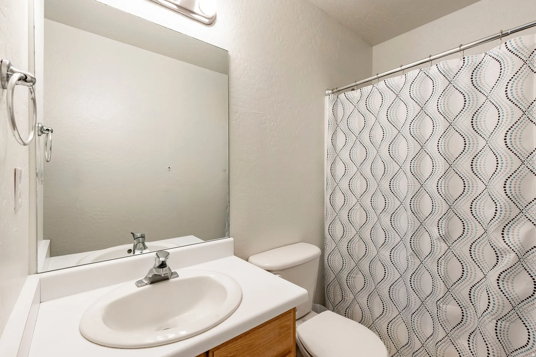 Bathroom featuring a vanity with an integrated sink, a large wall-mounted mirror, and a full-size toilet