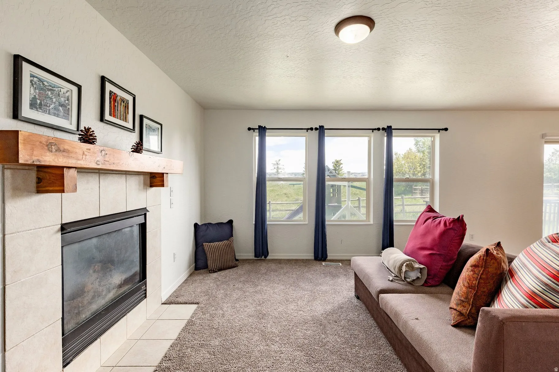 Living area featuring a gas fireplace with a wood mantel, tile surround, and an integrated hearth