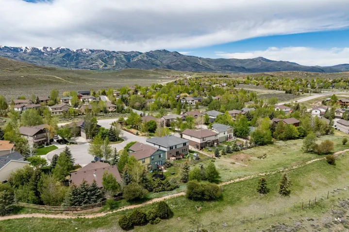 Residential neighborhood with varied architectural styles, mature trees, and natural landscaping, set against a backdrop of distant mountains