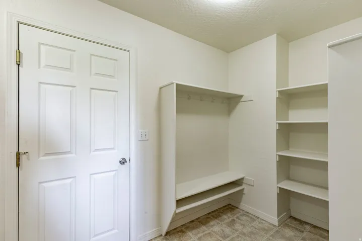Entryway featuring a six-panel door, built-in bench with storage, integrated coat hooks, open shelving, and tiled flooring