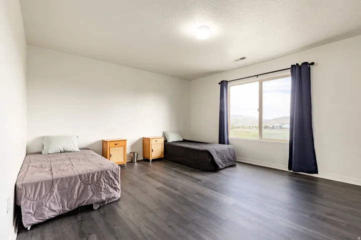 Spacious room featuring dark wood-finish flooring, a large window with horizontal muntins, white baseboards, and a neutral wall color
