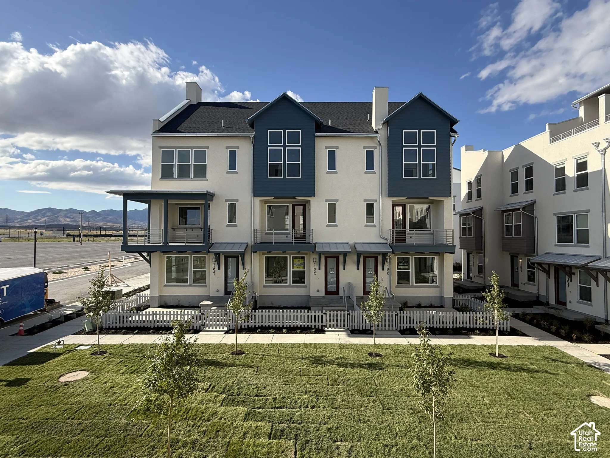 Contemporary townhome with a dark roof and light-colored stucco exterior