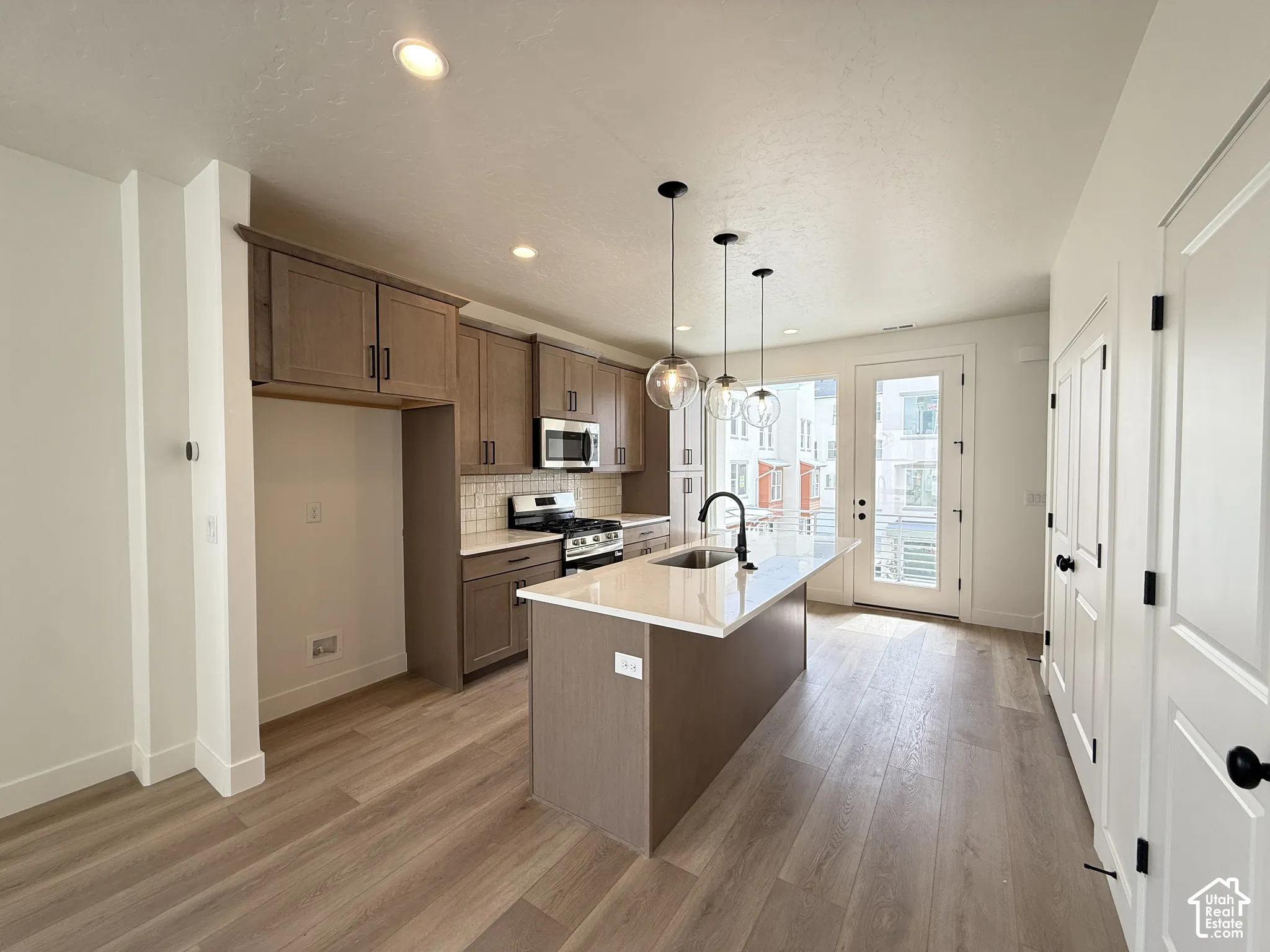 Kitchen featuring wood-finish flooring, recessed lighting, and a center island with a sink