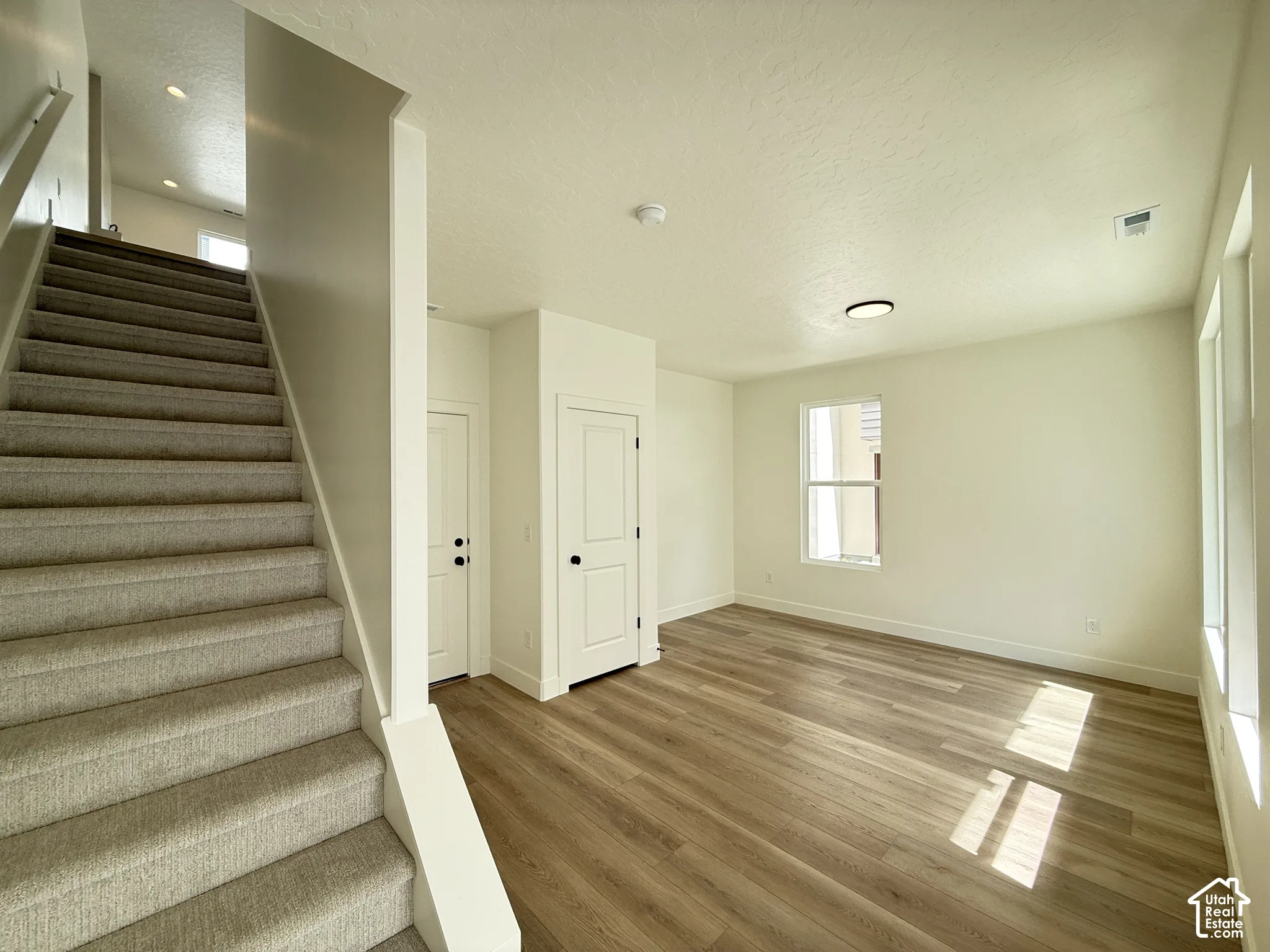 Wood-finish flooring, two-panel interior doors, carpeted staircase, and recessed ceiling lighting