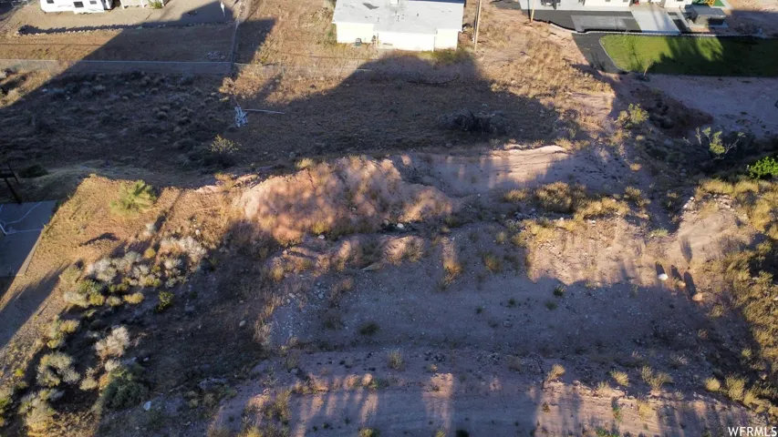 Expansive undeveloped lot featuring varied topography with natural vegetation, rock formations, and visible dirt paths
