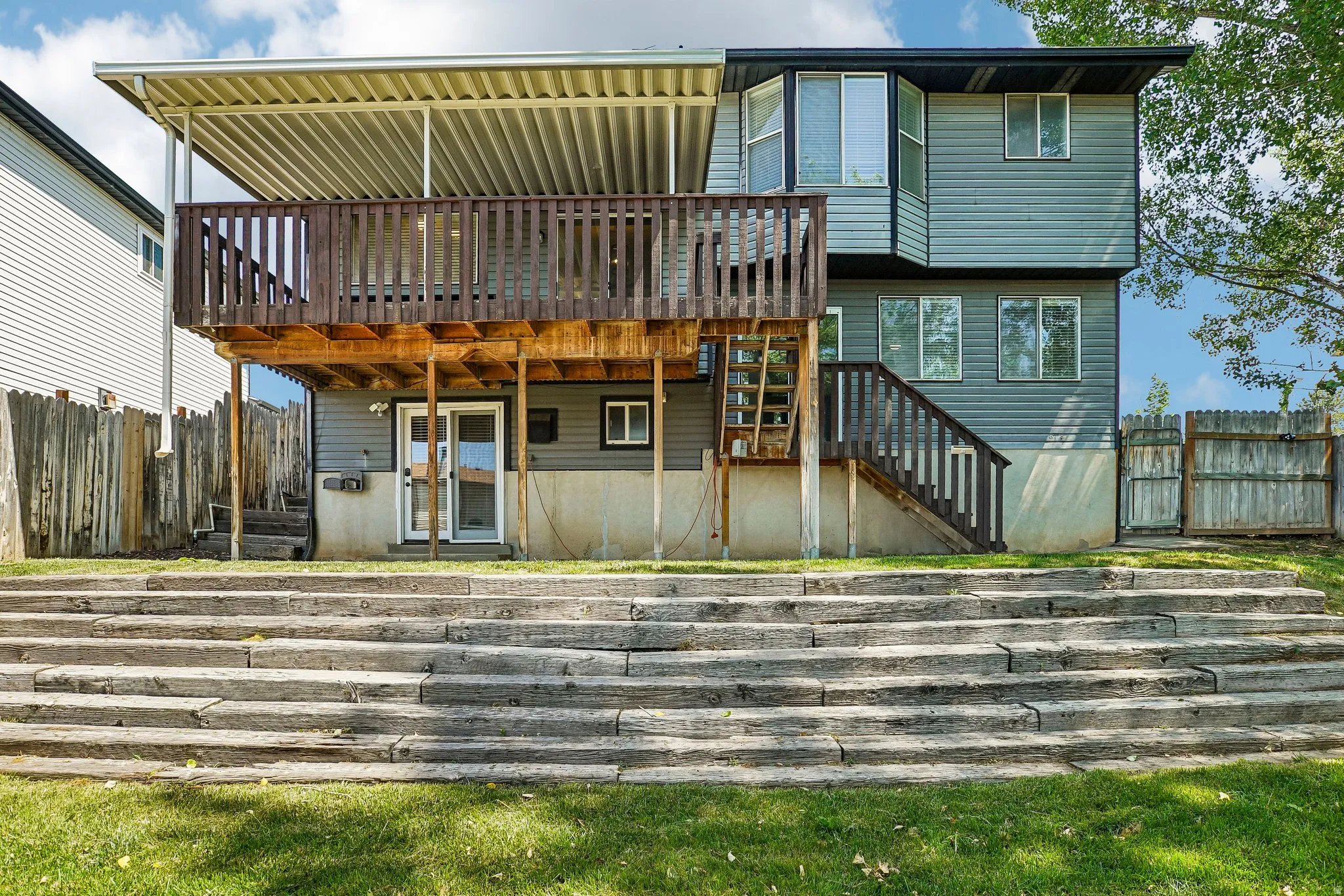 Multi-level property exterior featuring a covered wood deck, a bay window, and a ground-level patio door