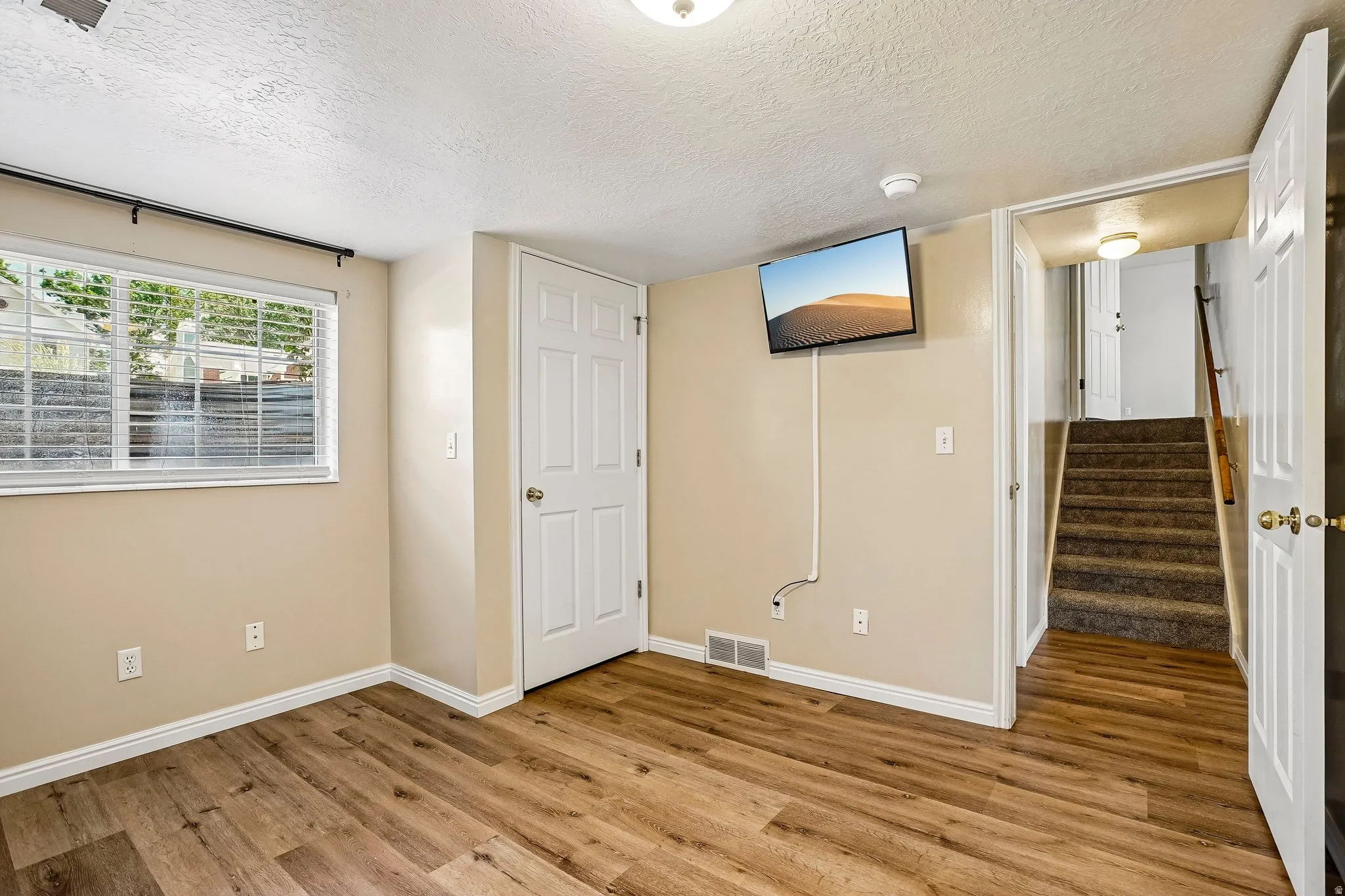 Room featuring wood-finish flooring, neutral wall tones, and white baseboards