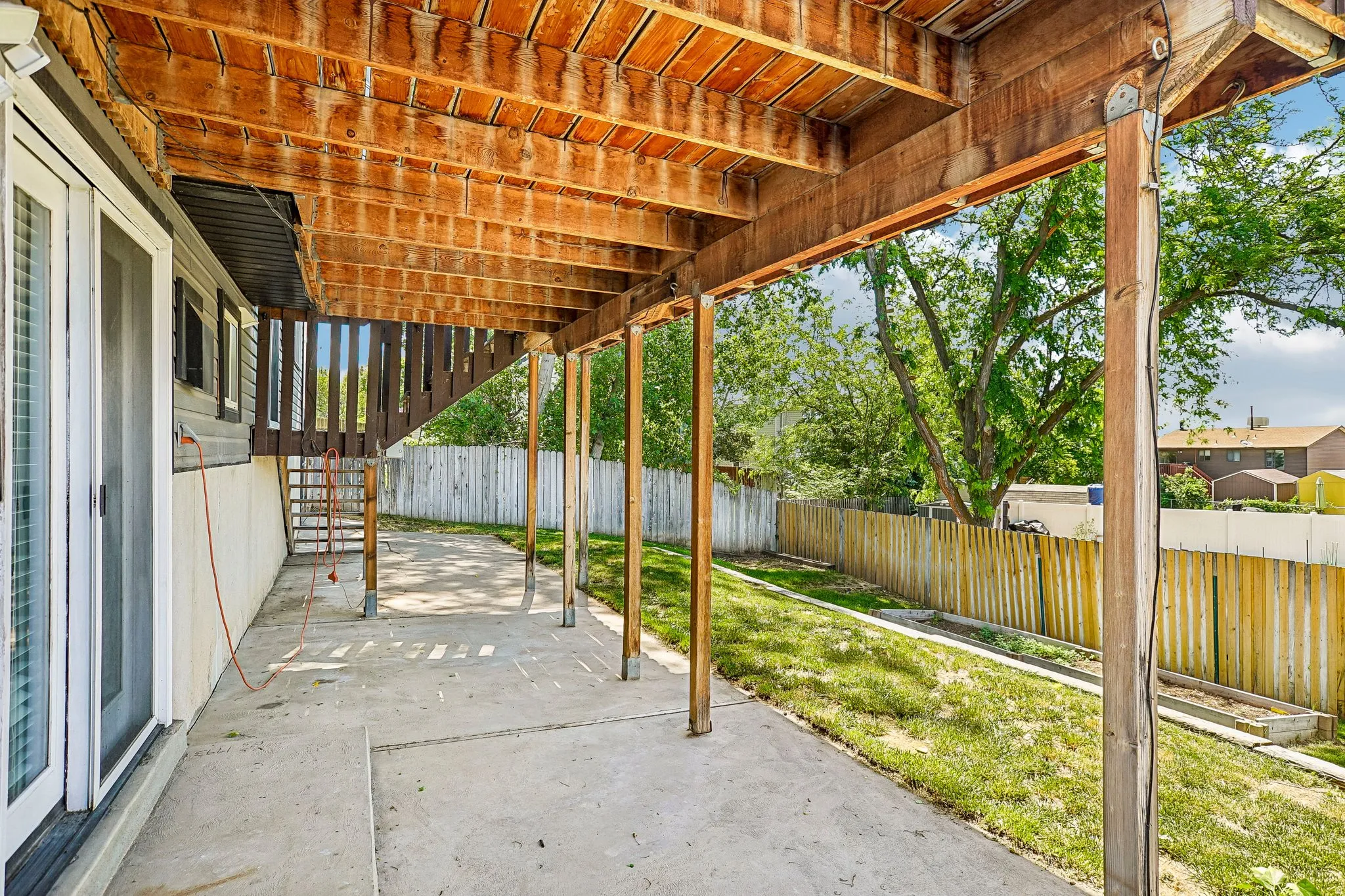 Covered patio area featuring a concrete slab and wood beam supports