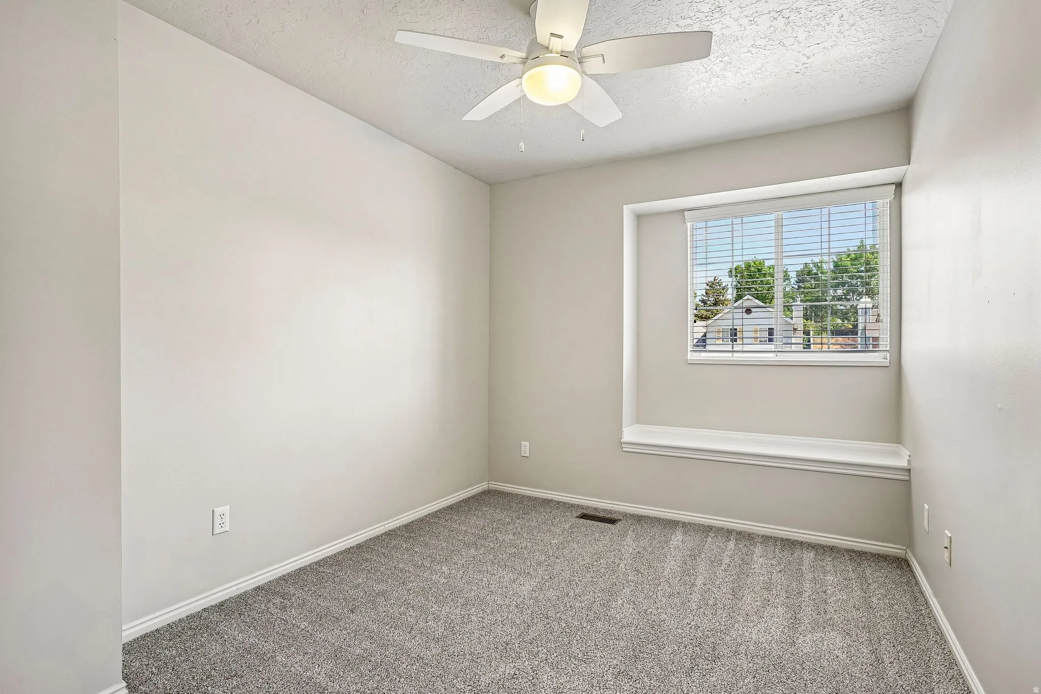 Neutral-toned room featuring a window with integrated blinds and a built-in window seat