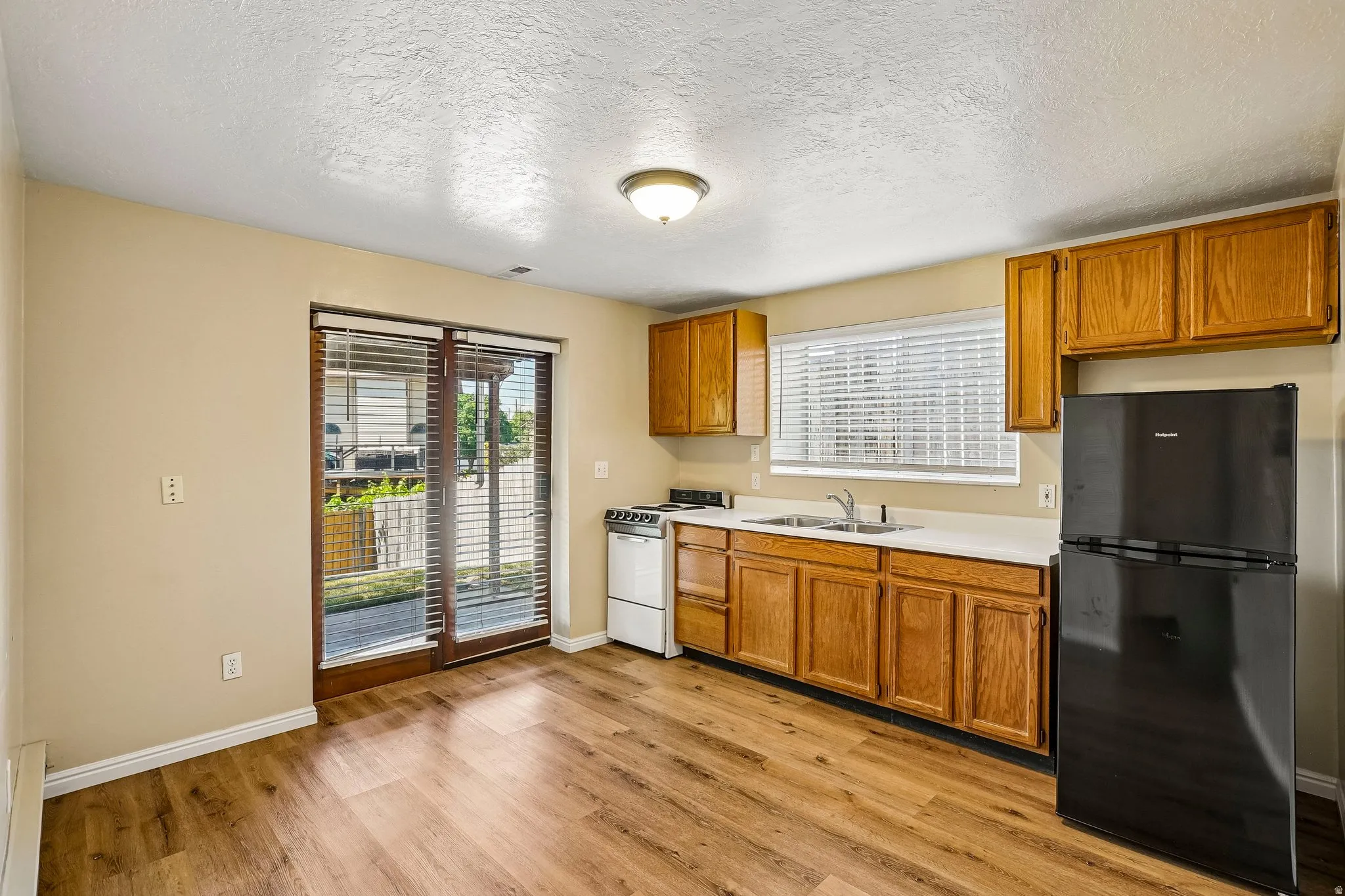 Kitchen area featuring wood-finish flooring, light-toned cabinetry, and a sliding glass door