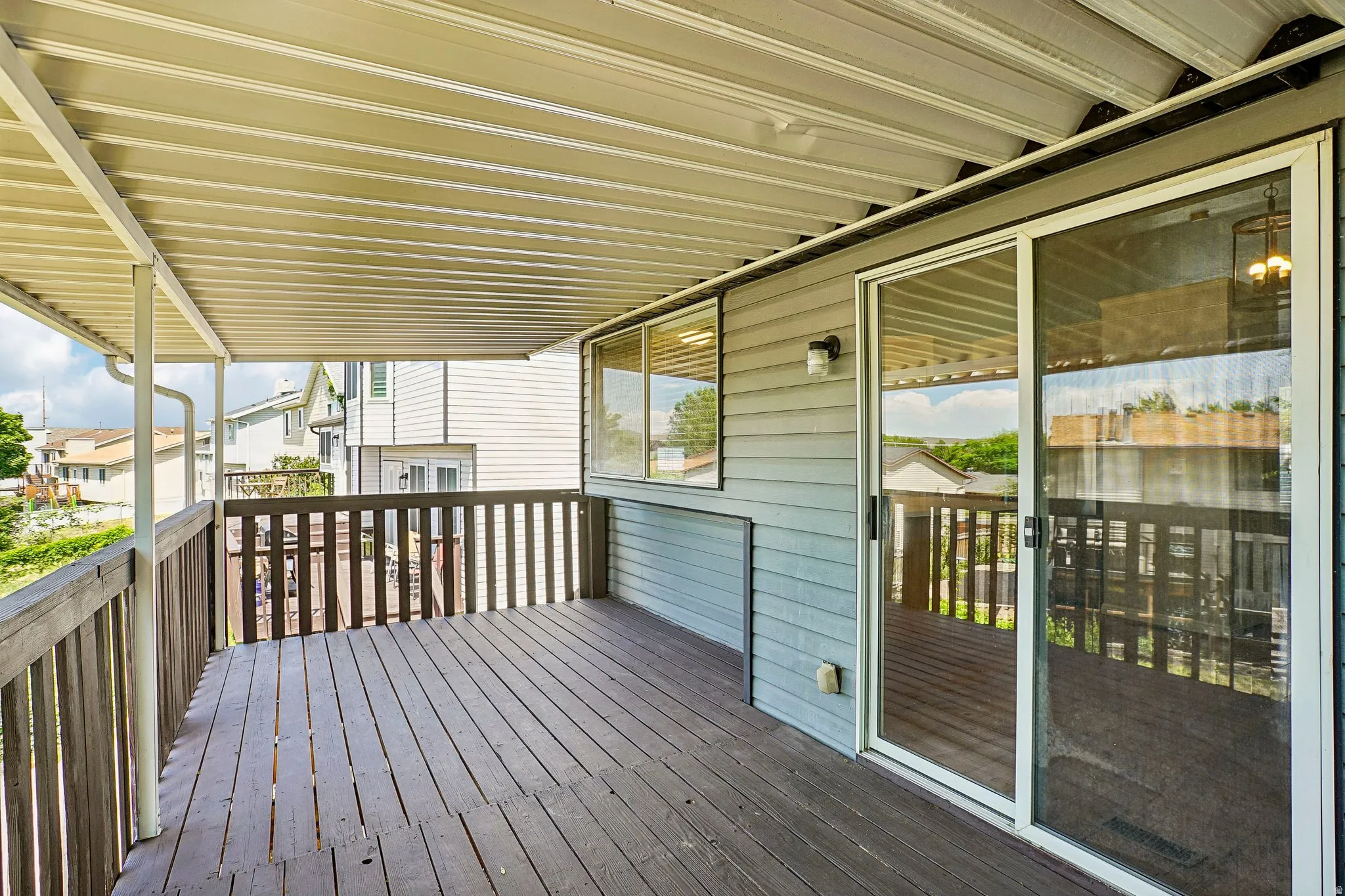 Spacious covered deck featuring wood-finish flooring, a wood railing, and direct access through sliding glass doors