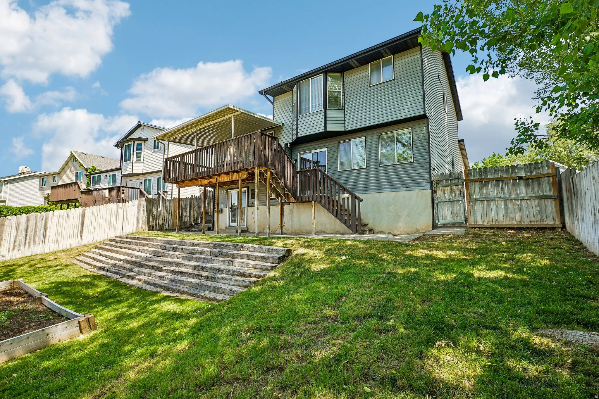 Multi-level backyard featuring wood-finish terraced retaining walls, a raised garden bed, and a full privacy fence