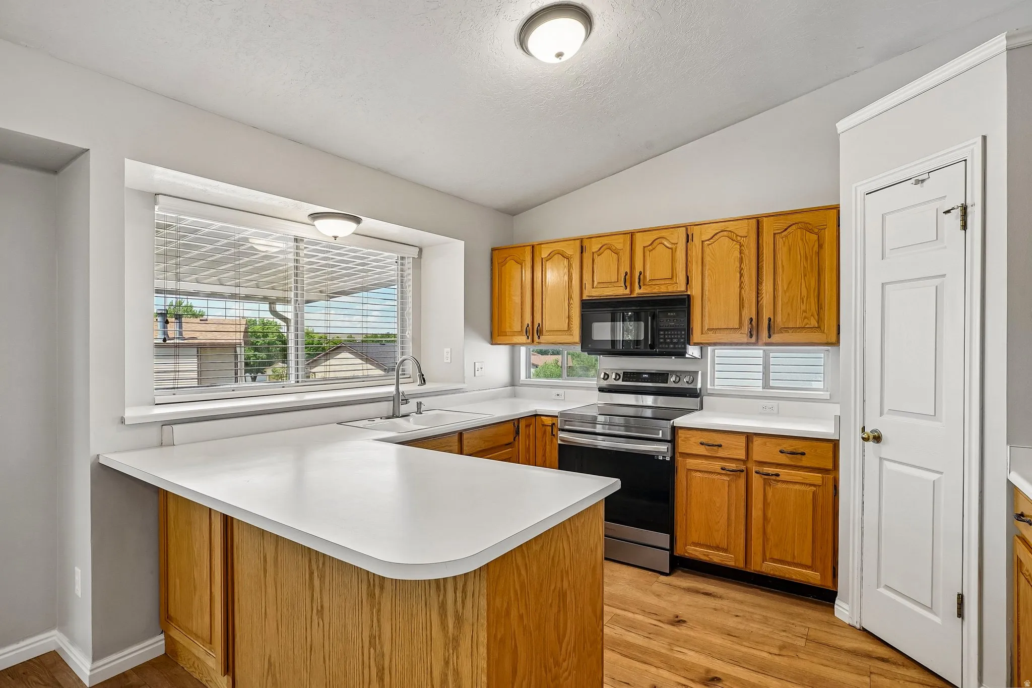 Kitchen featuring wood-finish flooring, light-toned countertops, and wood cabinetry