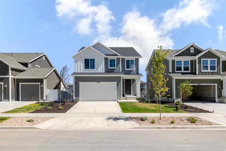 Two-story property with gray horizontal siding and white vertical siding accents, featuring a two-car garage and a paved driveway