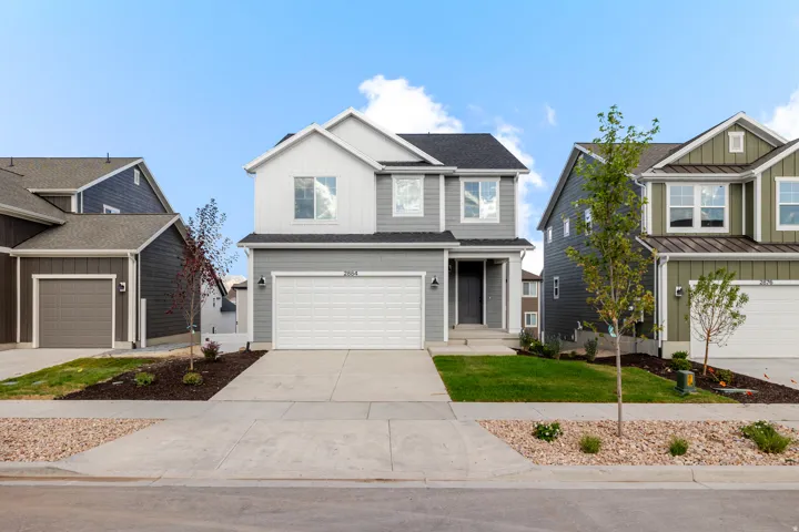 Two-story residence featuring a light gray and white façade, an attached garage, and a concrete driveway