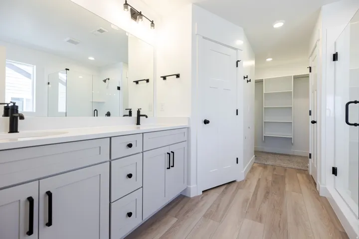 Dual vanity with matte black fixtures, light countertop, and light gray cabinetry