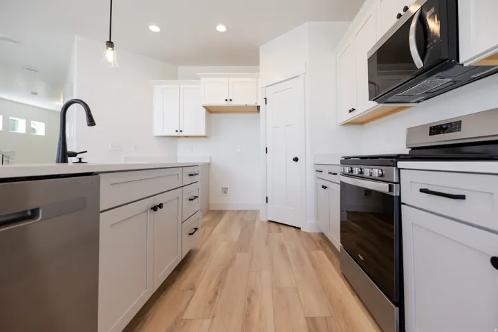 Kitchen featuring stainless steel appliances, wood-finish flooring, white cabinetry, a kitchen island, and recessed lighting