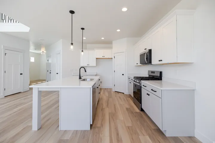 Kitchen featuring white cabinetry, light-toned wood-finish flooring, recessed lighting, a kitchen island with sink, and stainless steel appliances